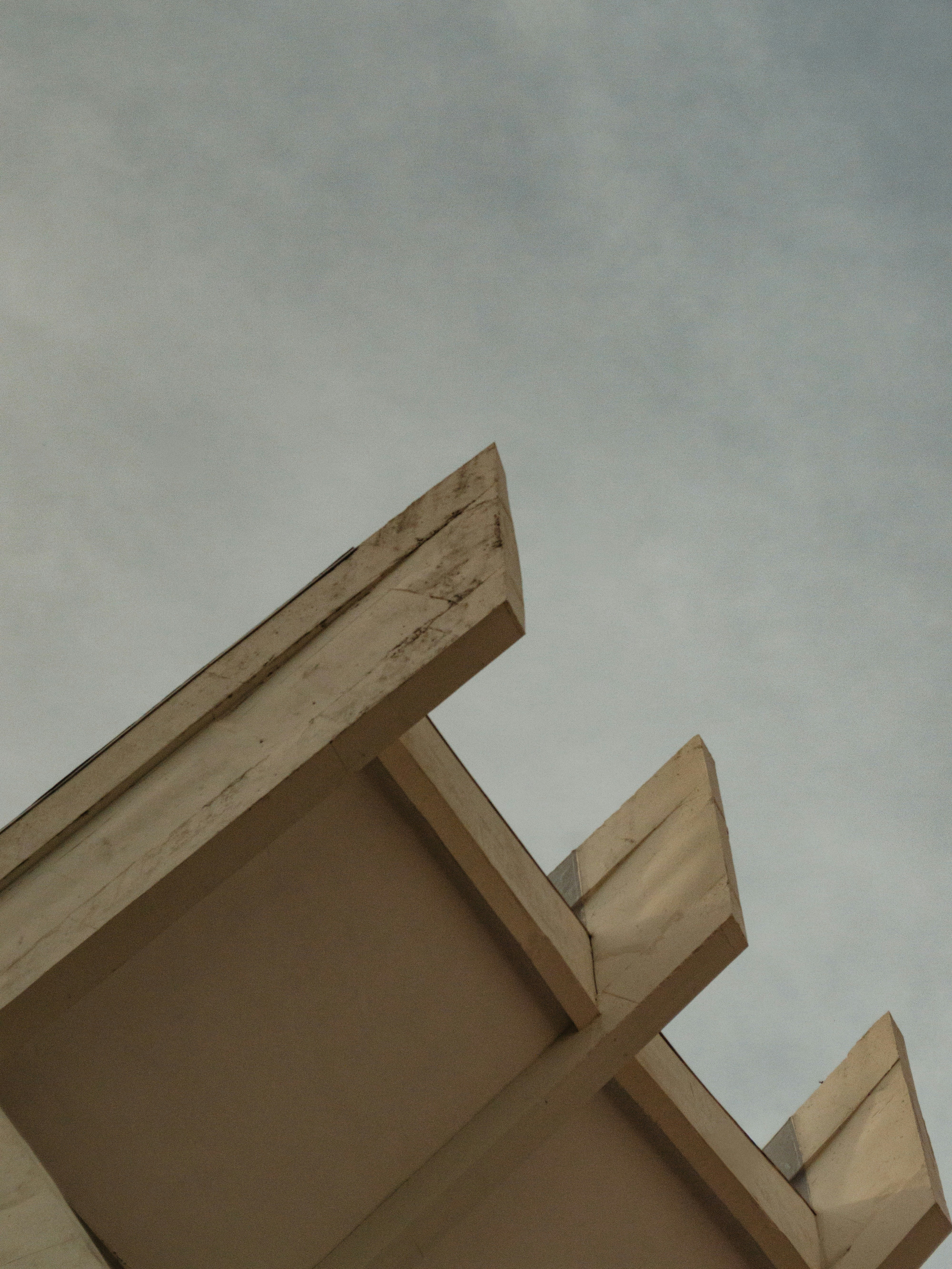 Geometric building eaves against a cloudy sky