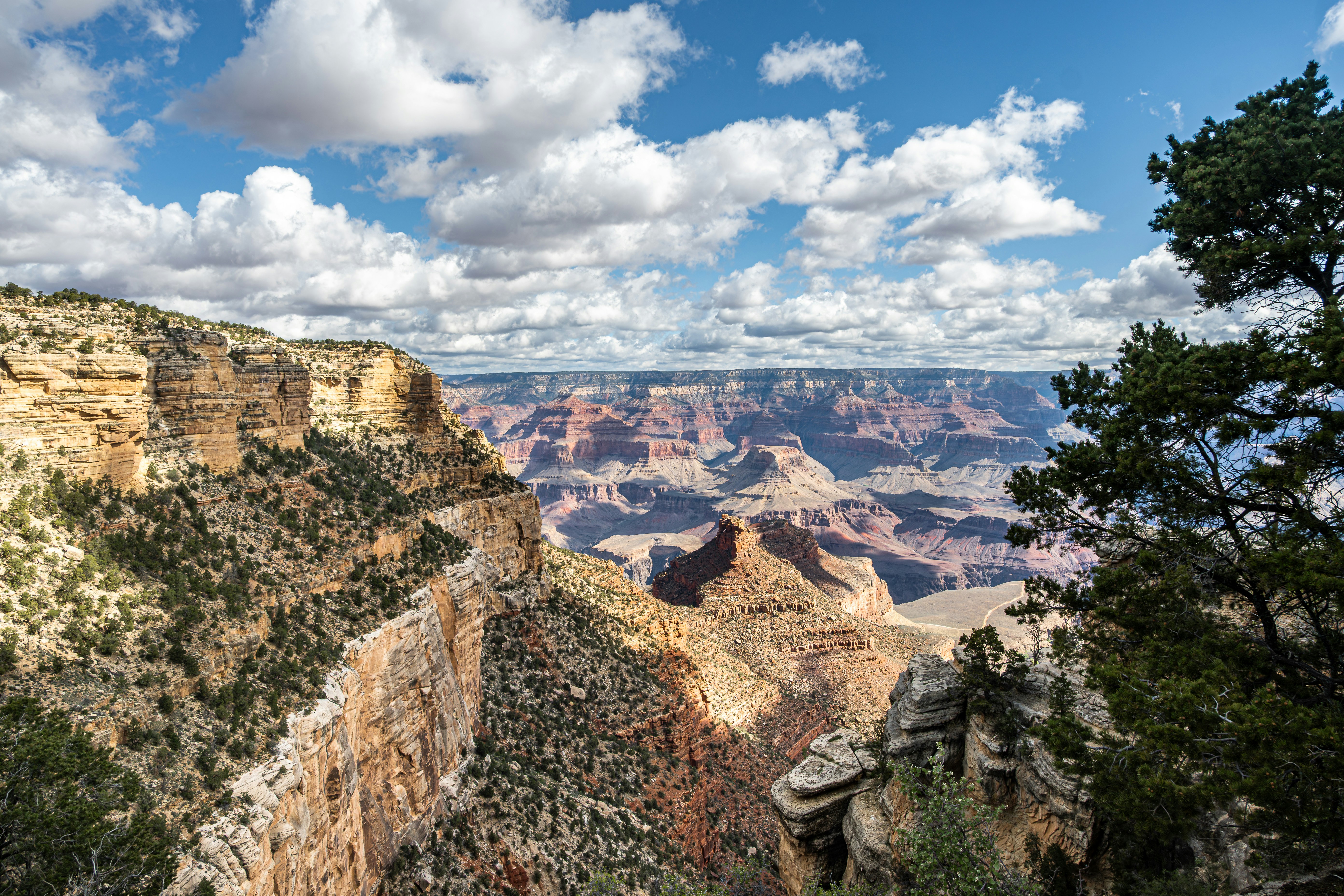 Vast canyon landscape with layered rock formations under clouds.