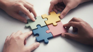 Hands connecting colorful puzzle pieces together.