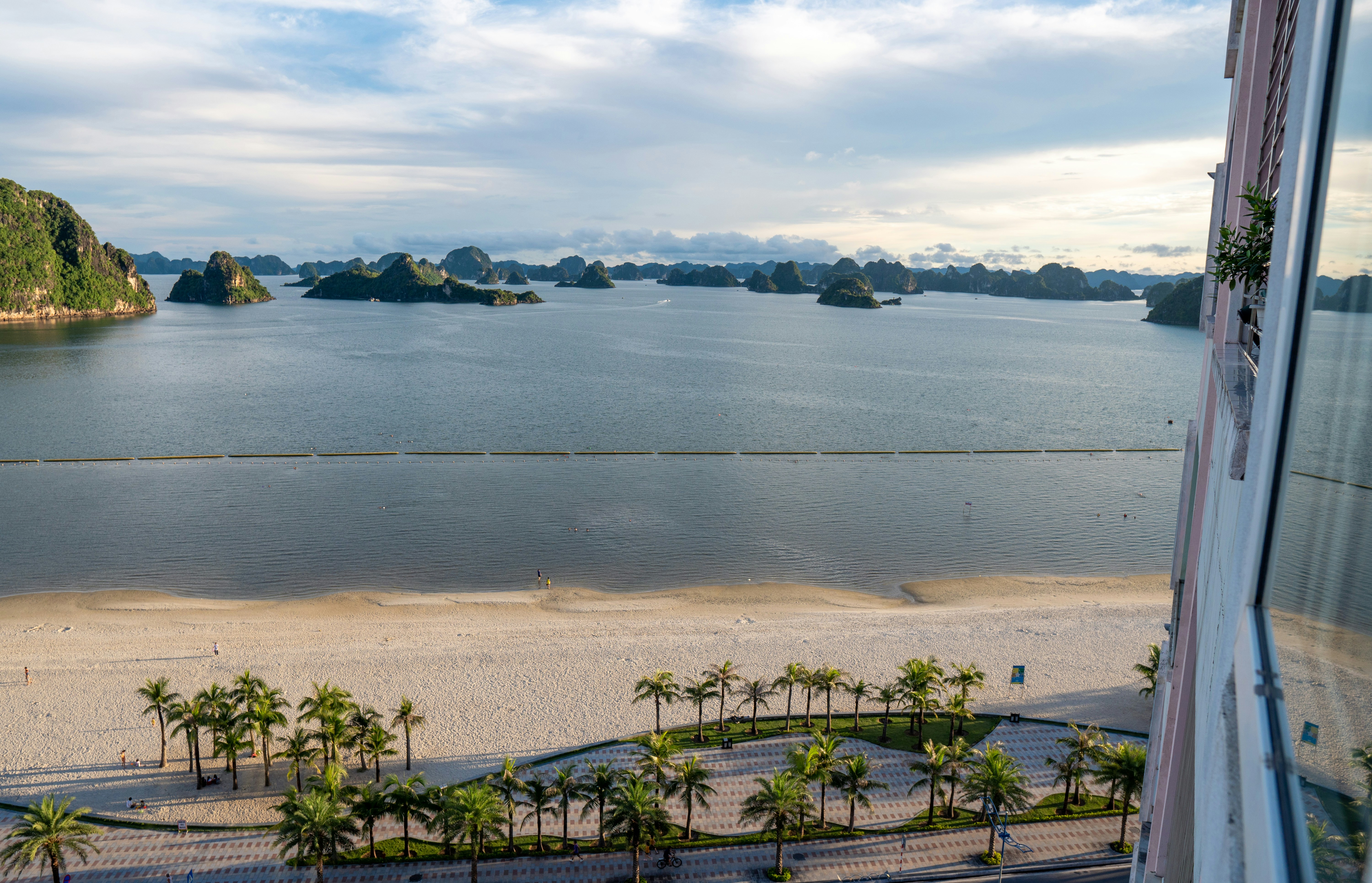Tropical beach with palm trees and limestone karsts in ocean.