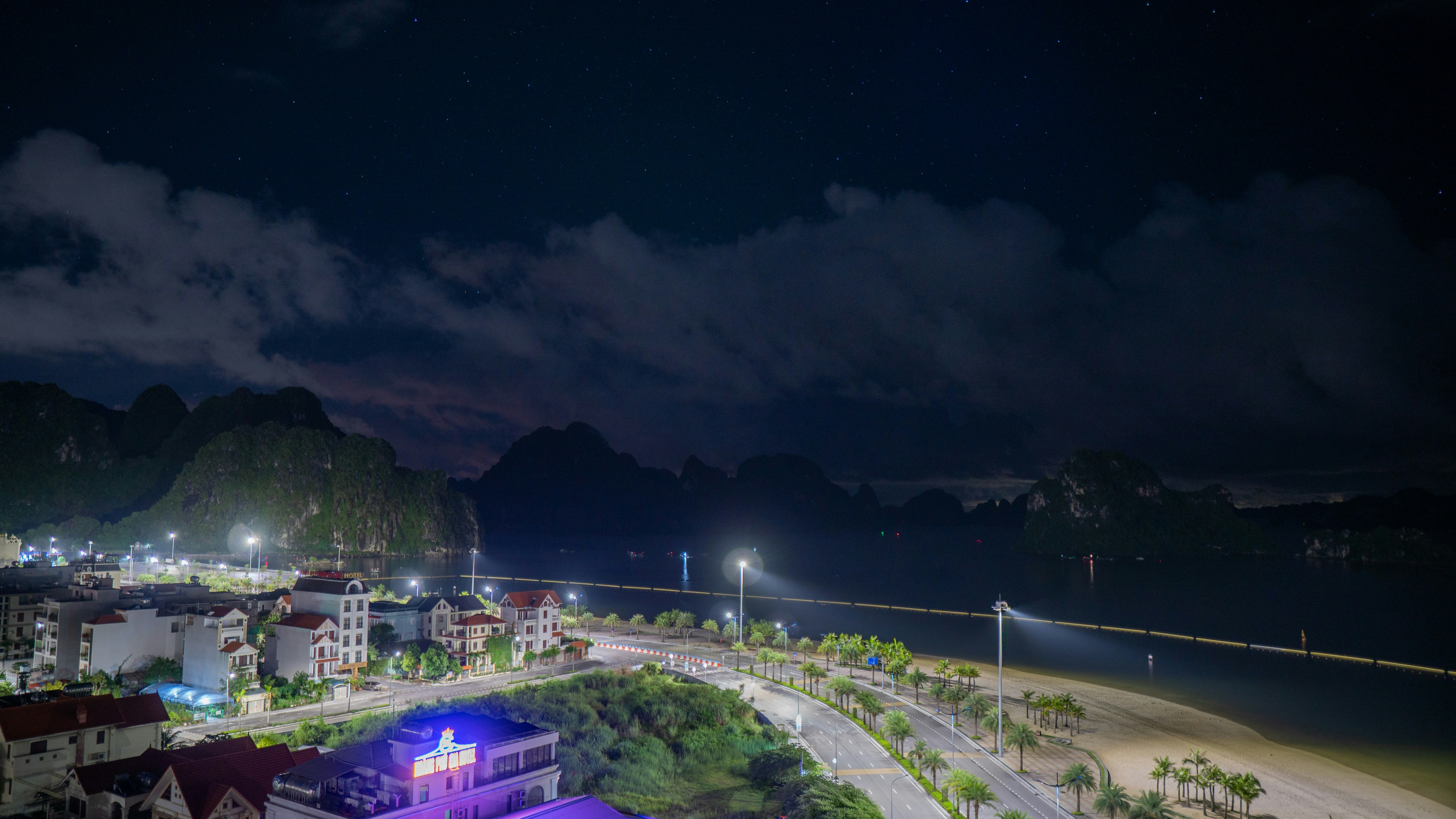 City lights illuminate a coastal town at night.
