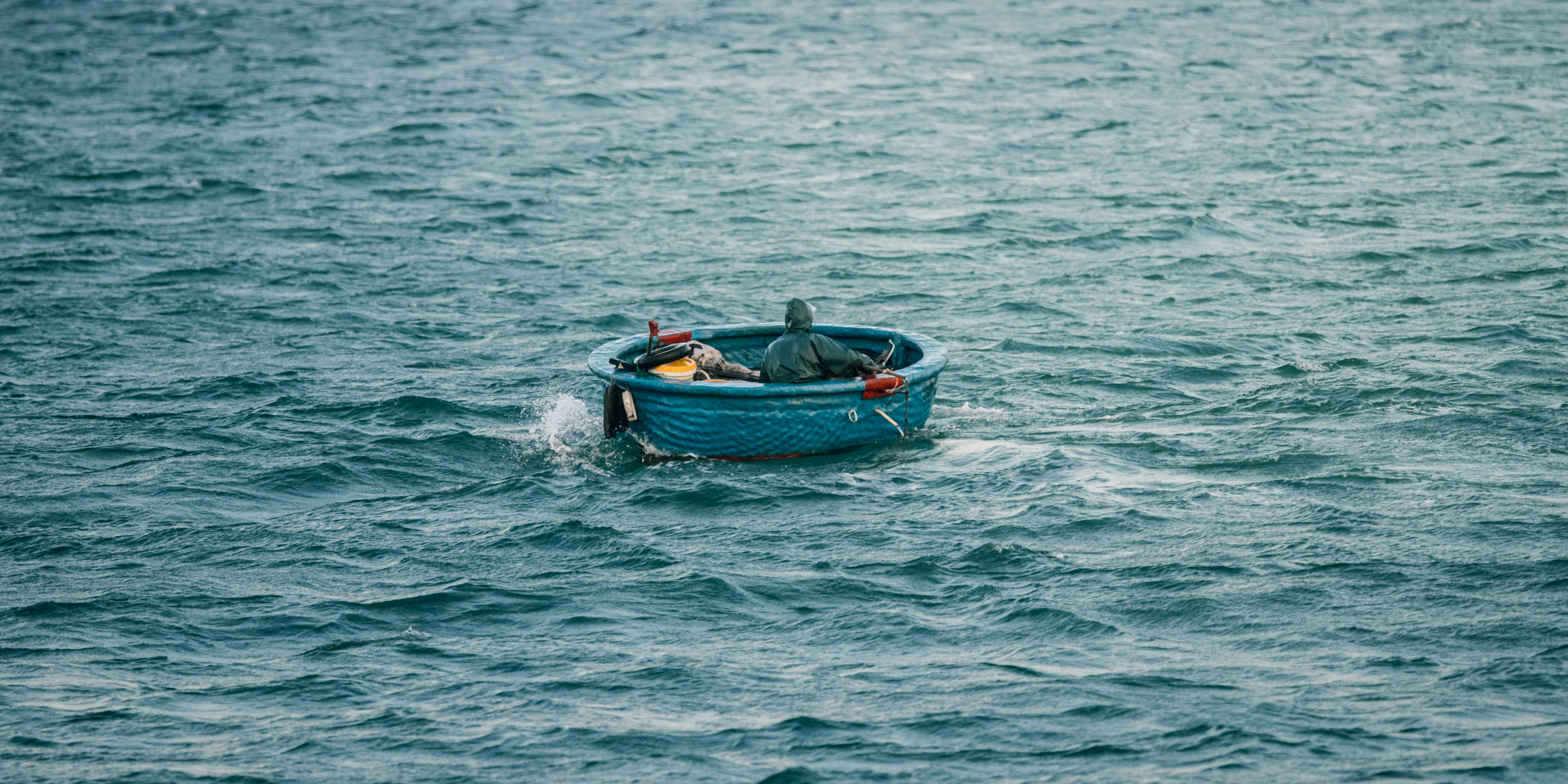 A small blue boat with two people on the sea