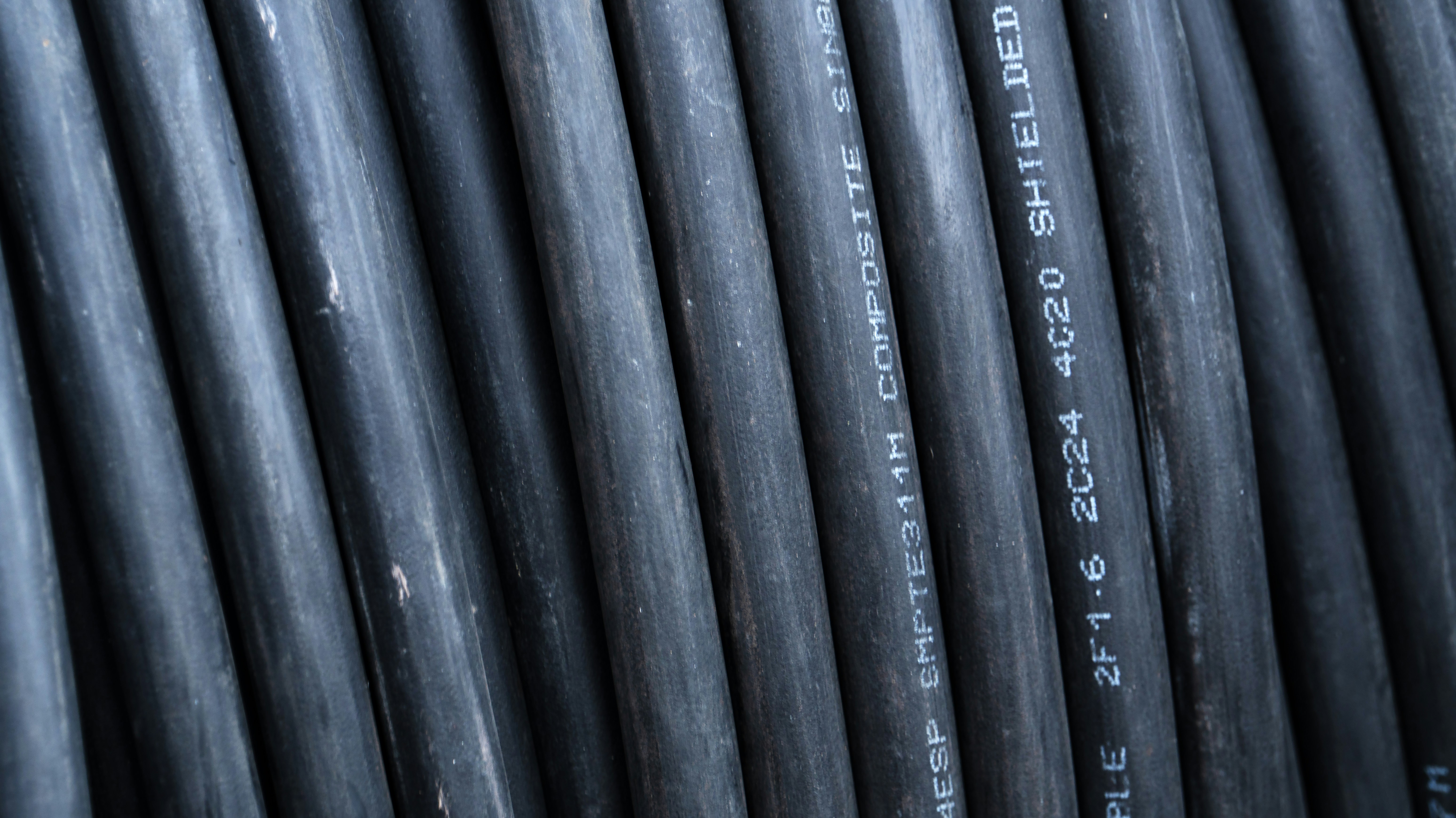 Close-up de cabos elétricos pretos com marcações de texto.