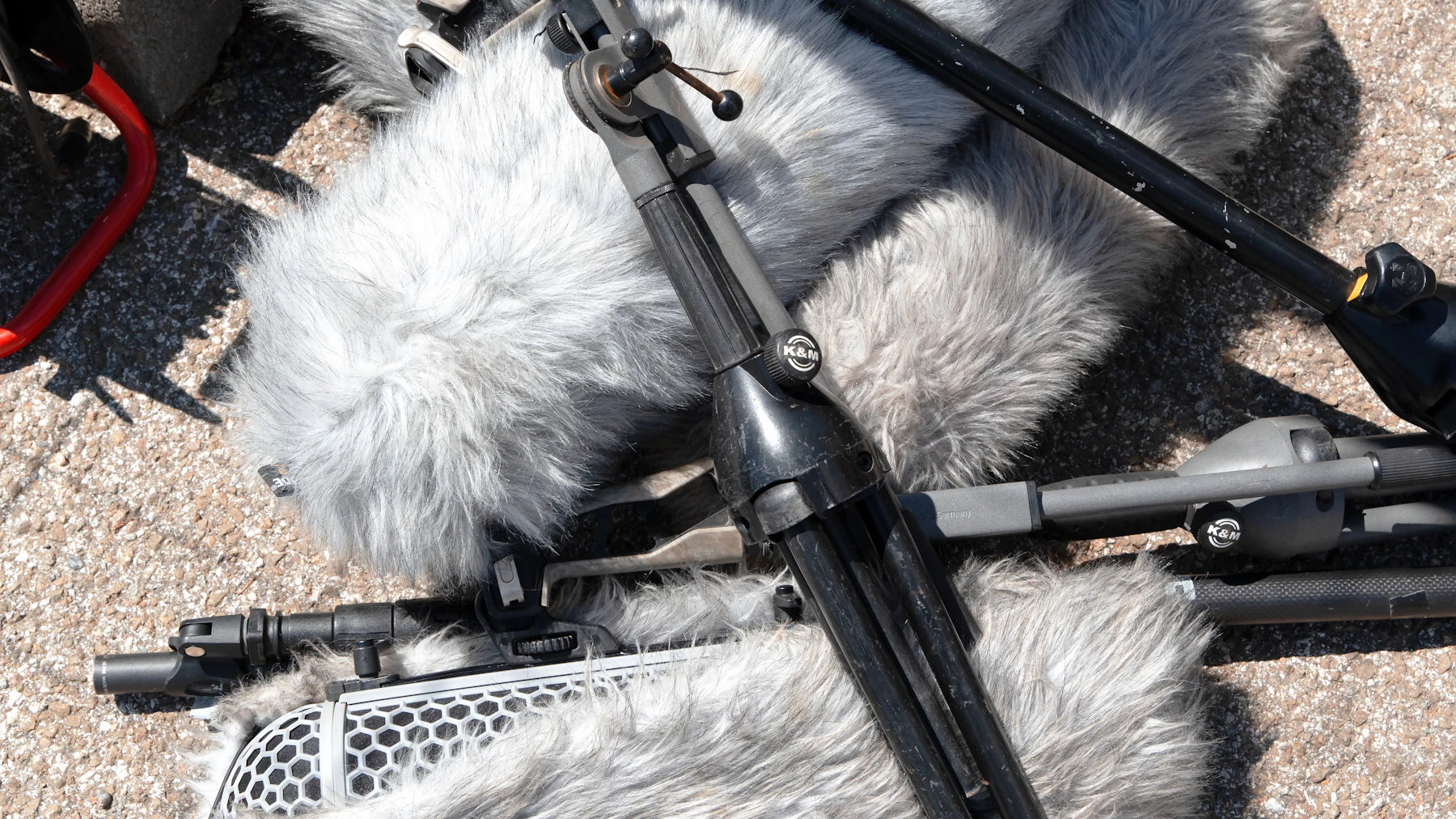 Grey furry microphone windscreens on boom poles lying on the ground