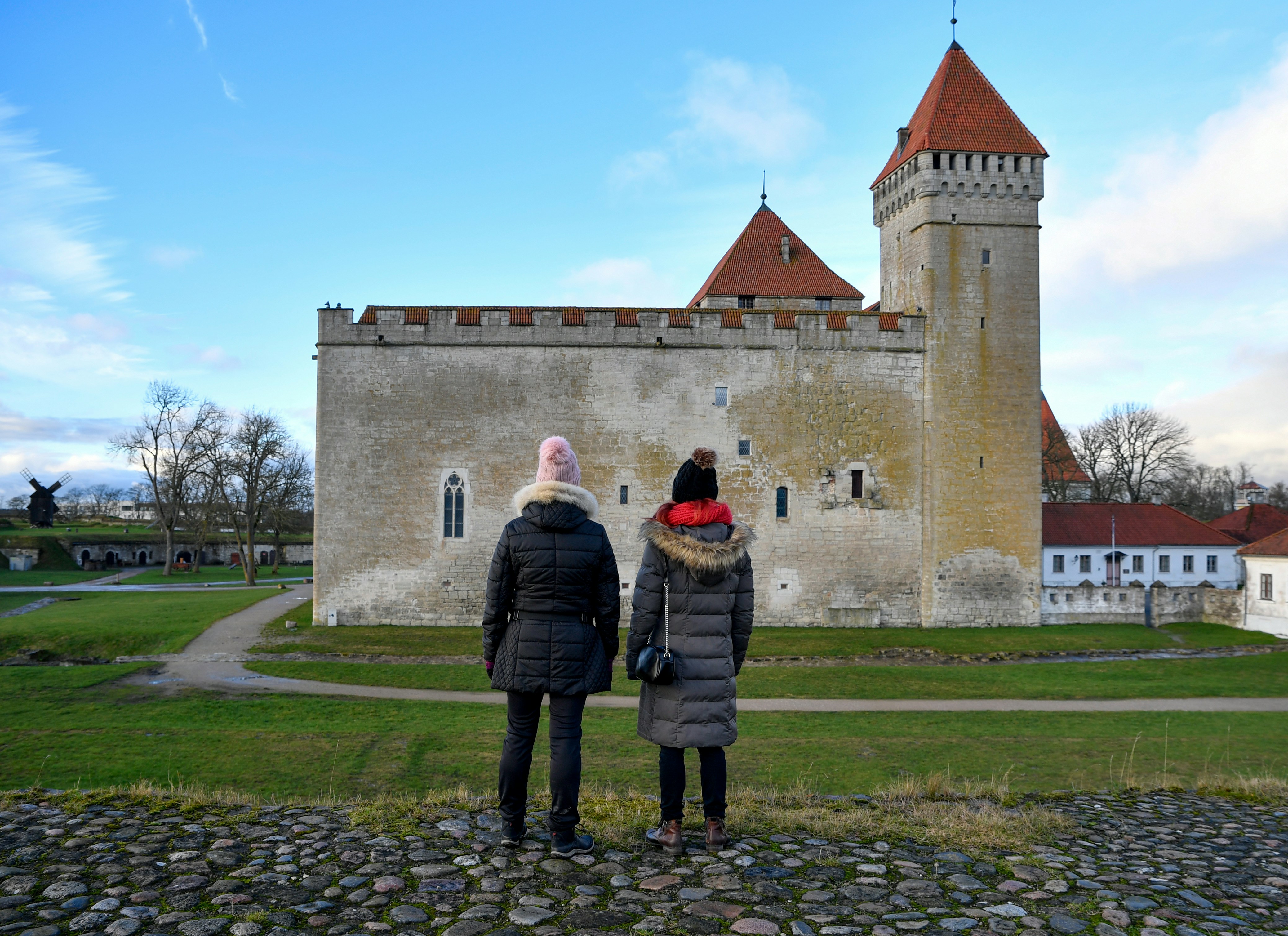 Two people stand before a historic stone castle.