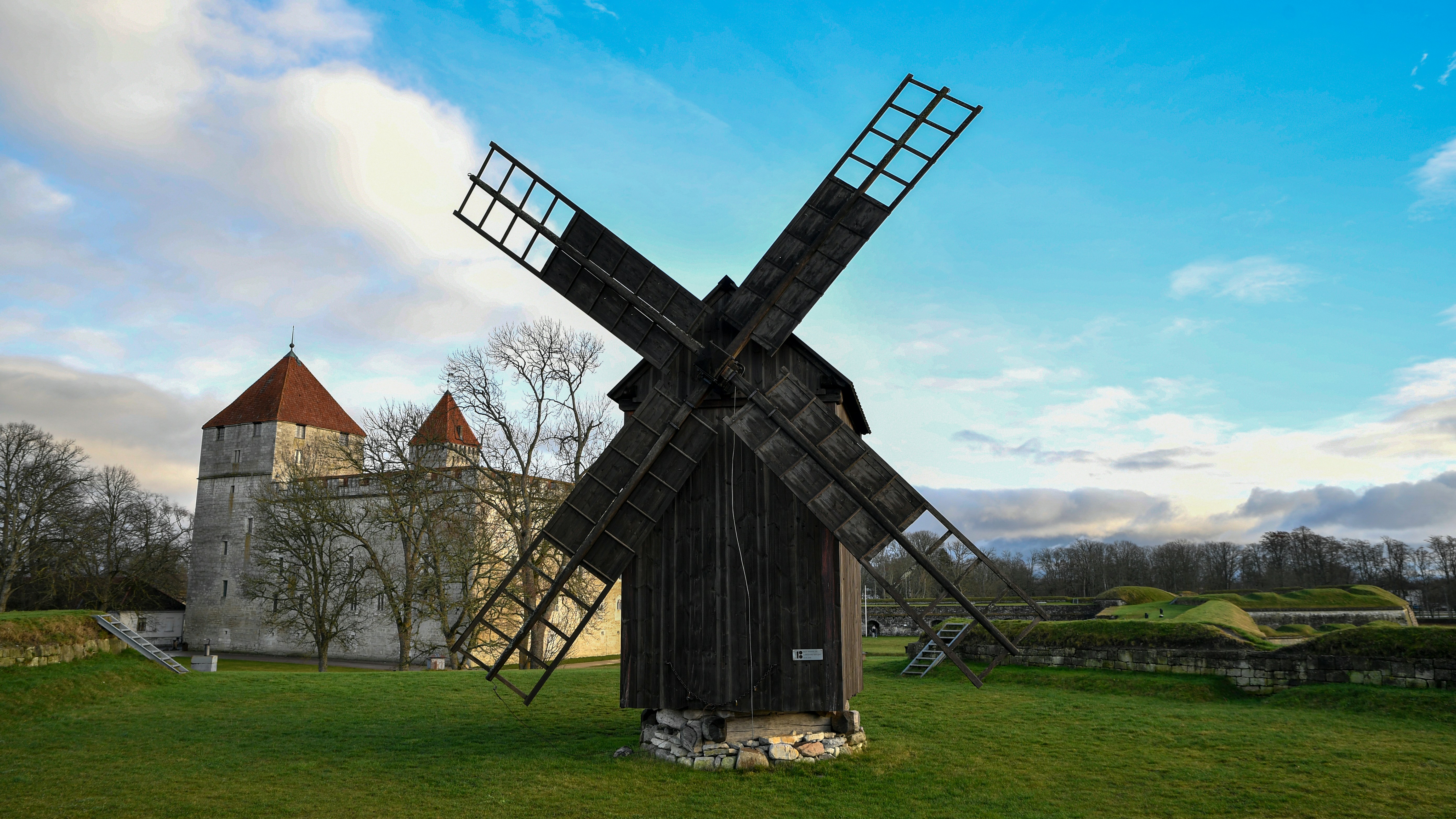 Old wooden windmill with stone building in background