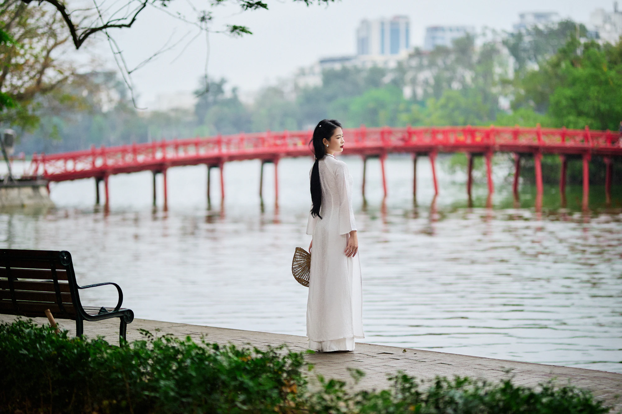 A woman in a white ao dai by the red bridge on Hoan Kiem Lake, Hanoi