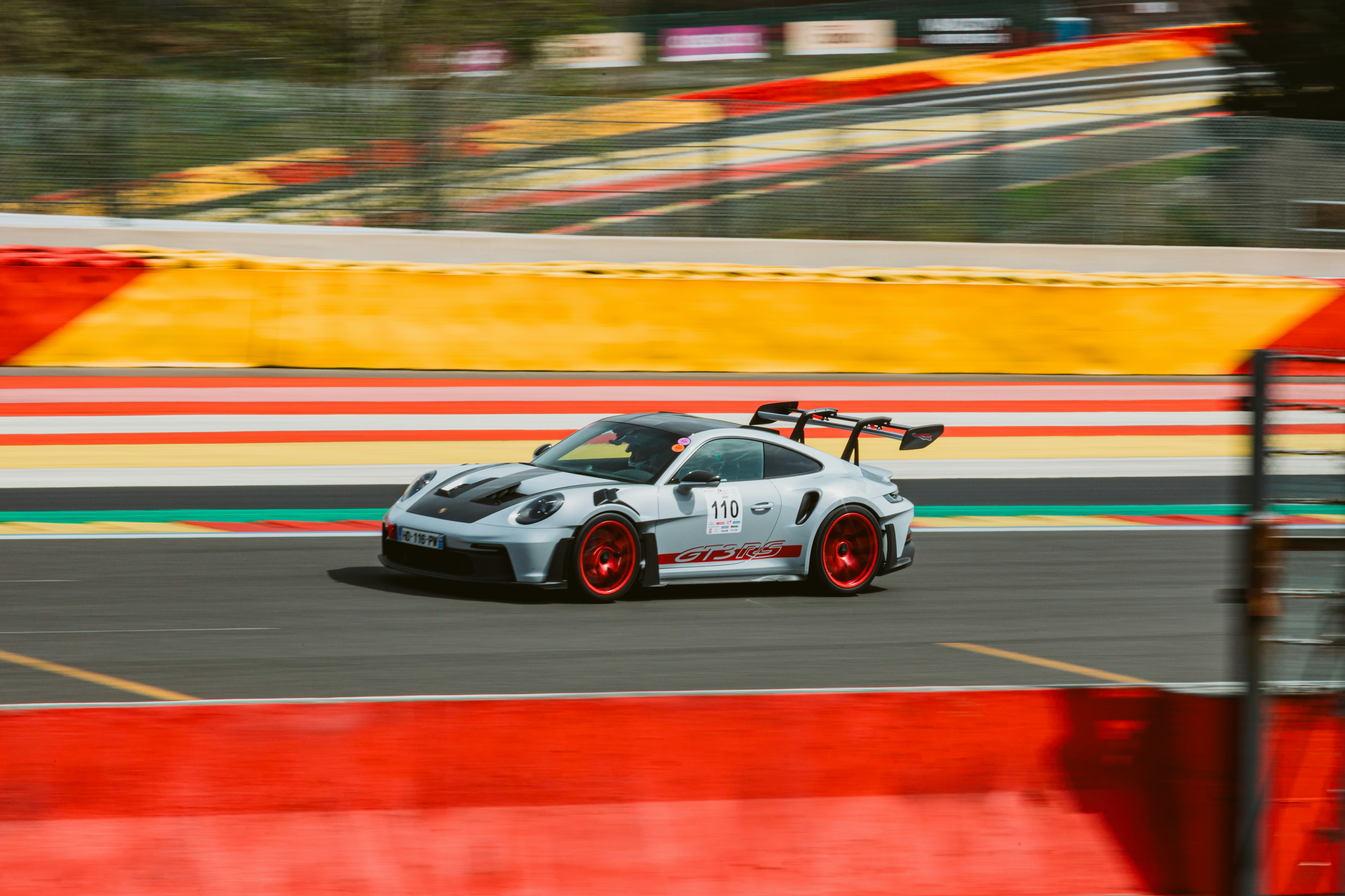 Une voiture de course blanche file à toute vitesse sur un circuit.