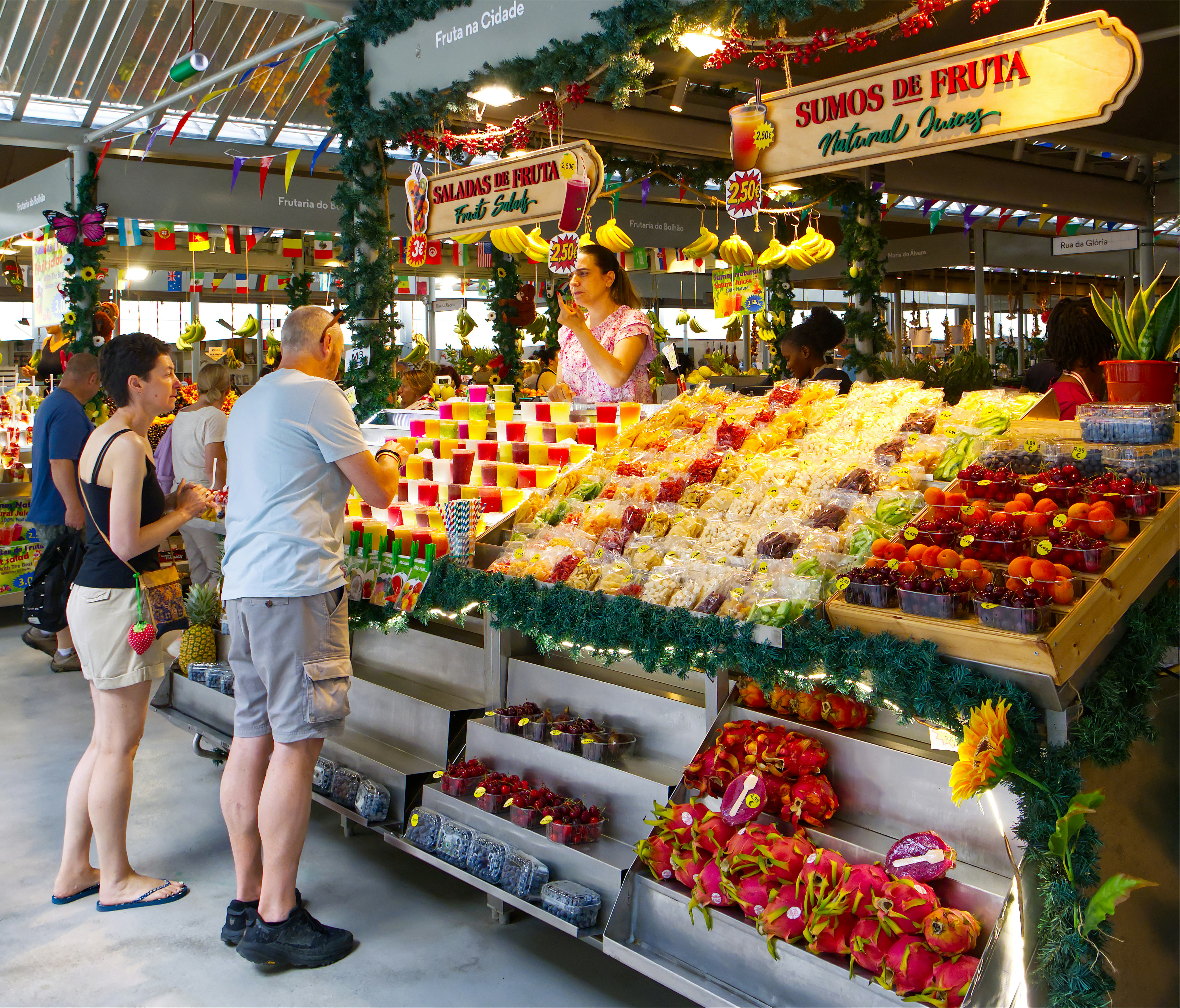 People buying fresh fruit and juices at a market stall