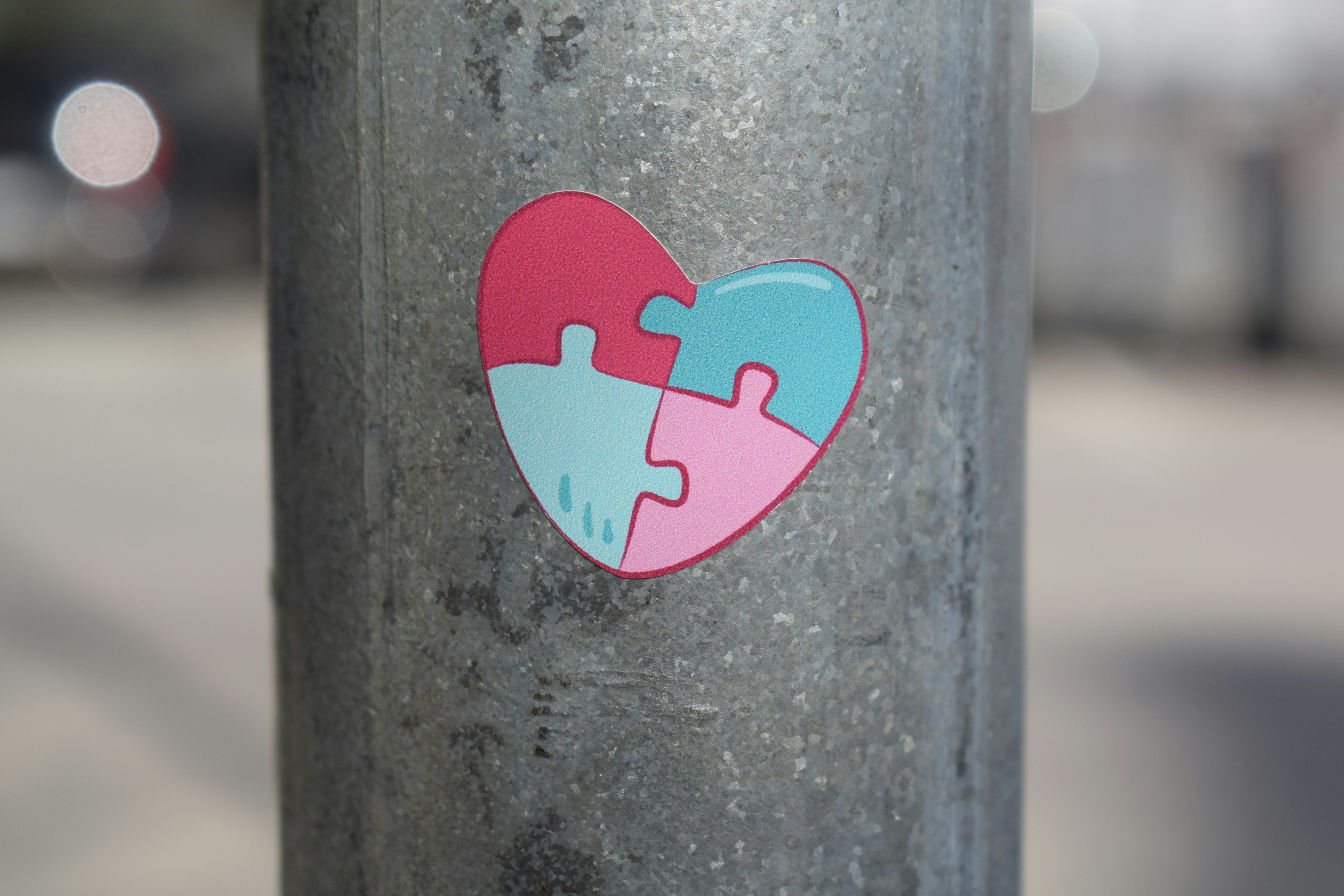 A heart-shaped puzzle sticker on a metal pole.