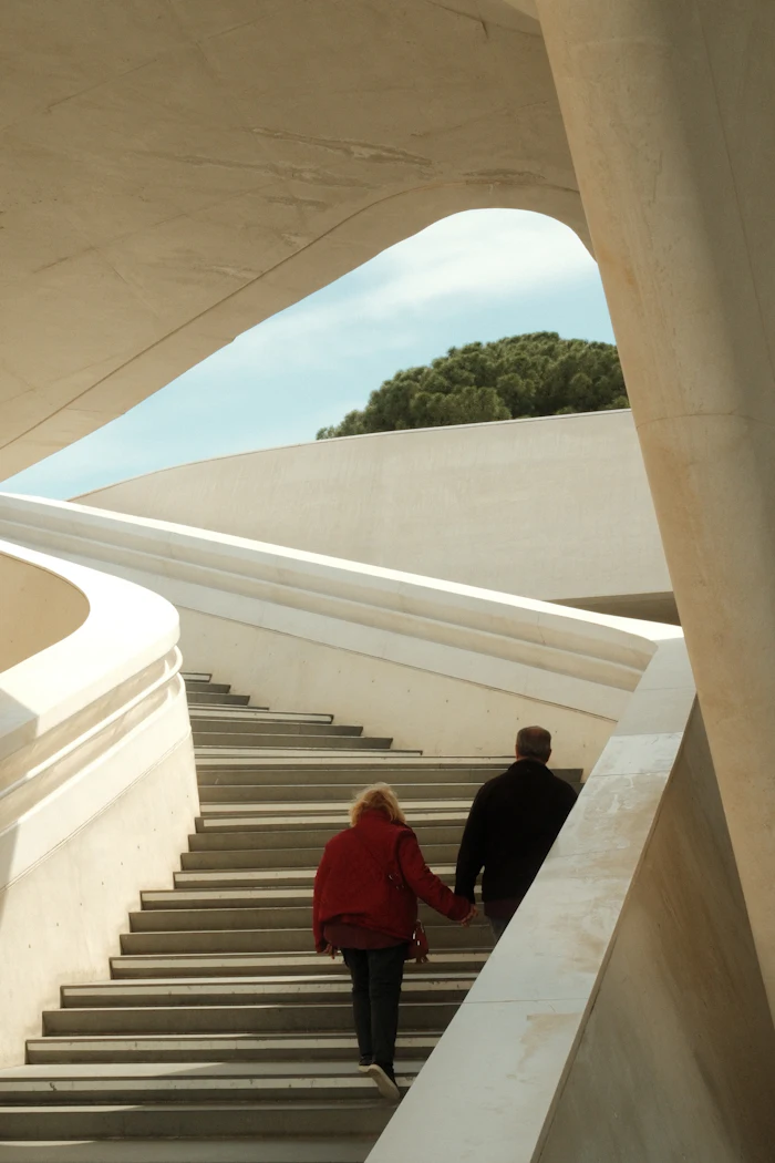 Pareja caminando de la mano por una escalinata de arquitectura contemporánea