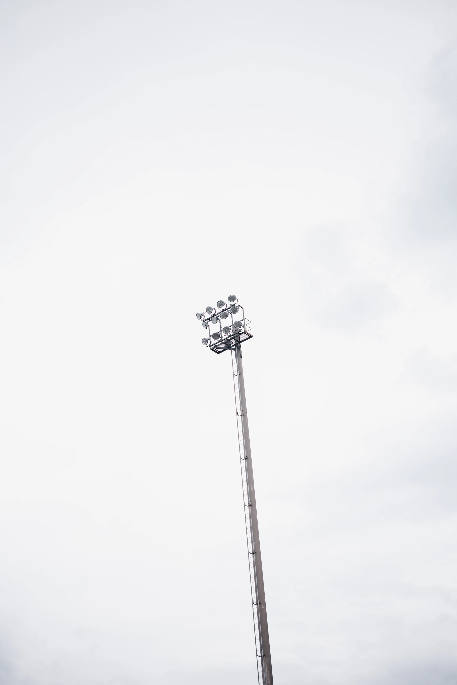 A tall stadium light pole against a cloudy sky.