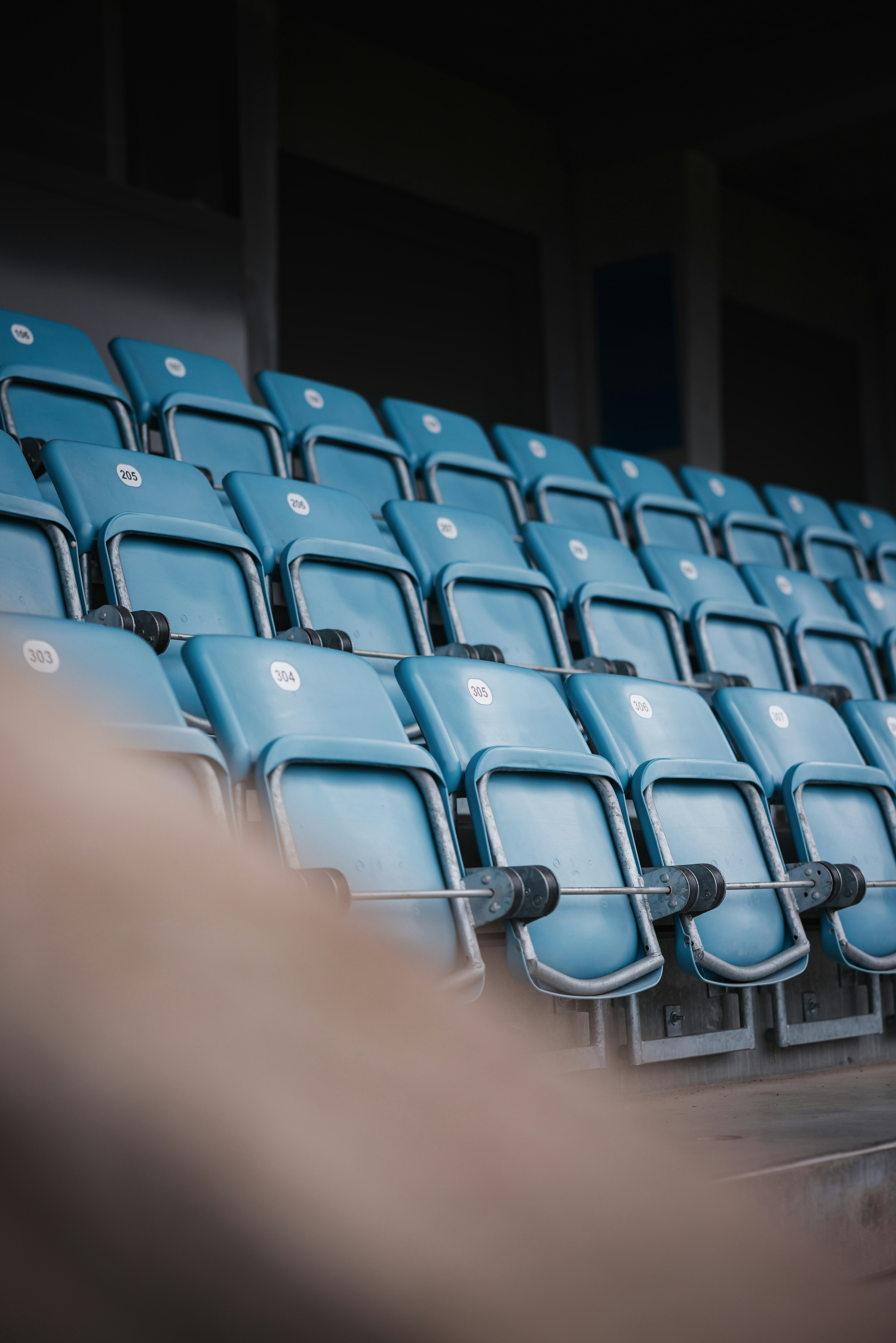 Reihen leerer blauer Stadionsitze mit Metallarmlehnen.