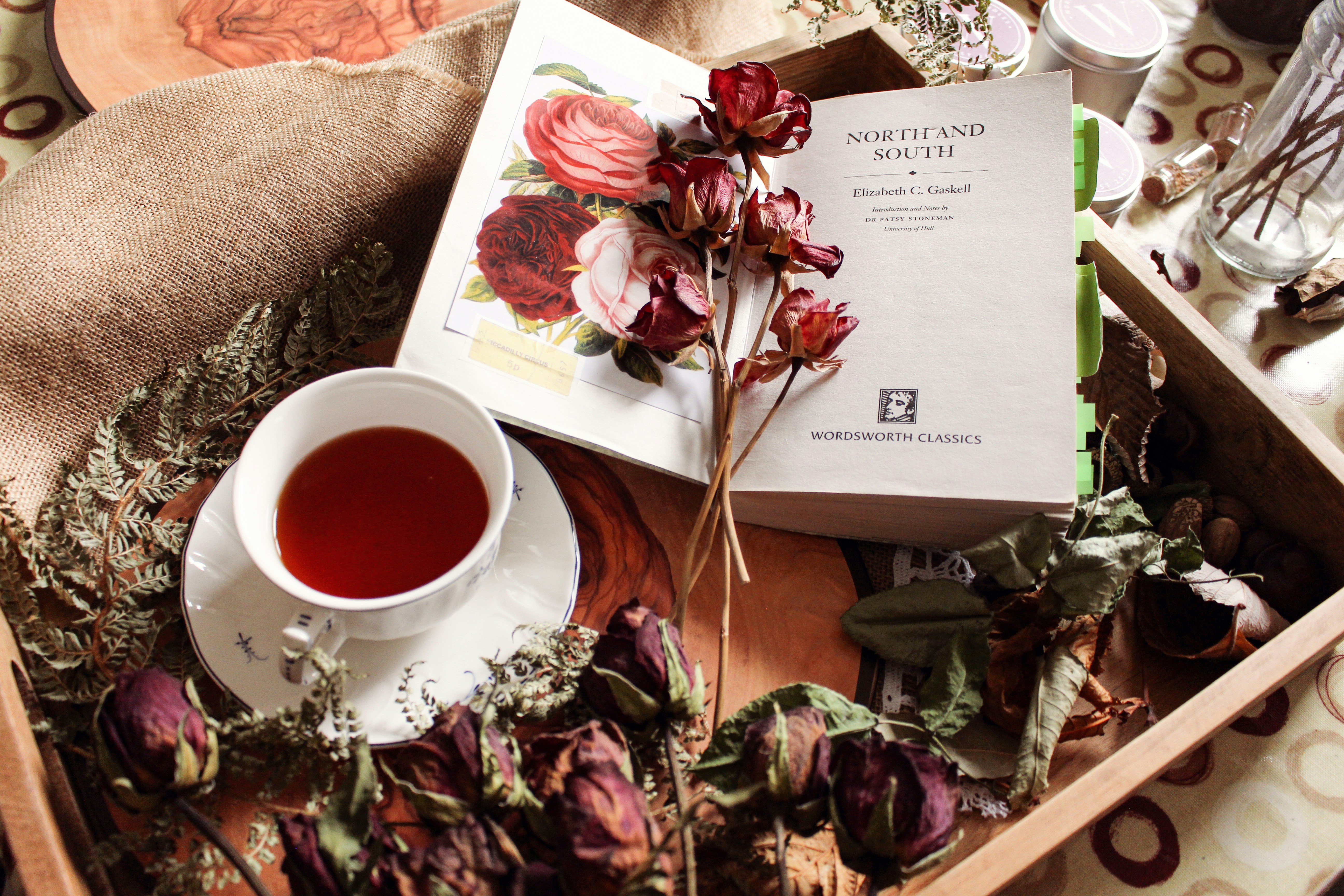 A cup of tea with dried flowers and a book.