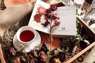 A cup of tea with dried flowers and a book.
