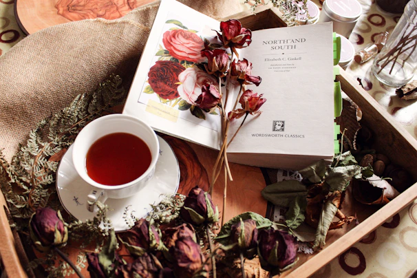 A cup of tea with dried flowers and a book.