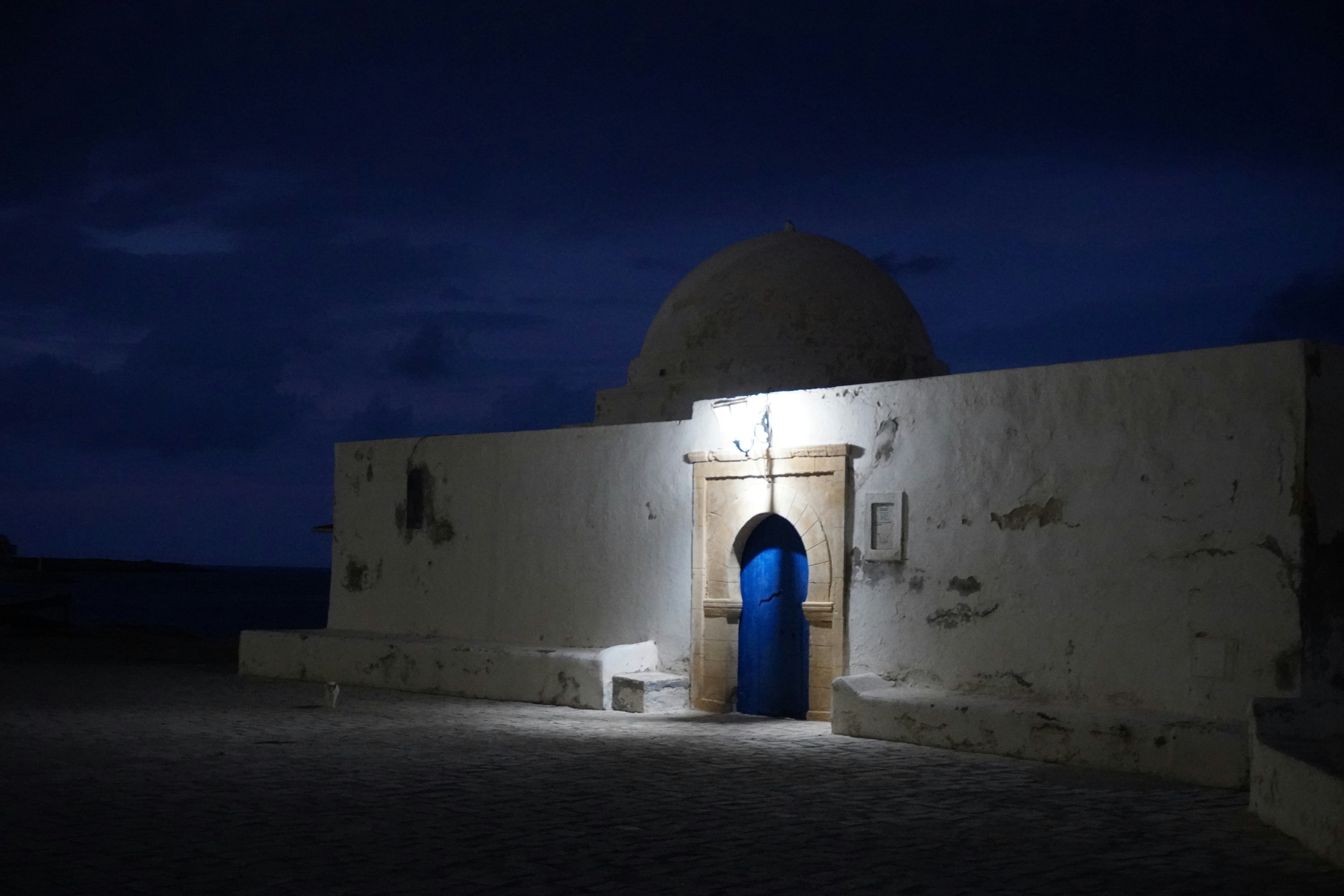 White building with blue door at night