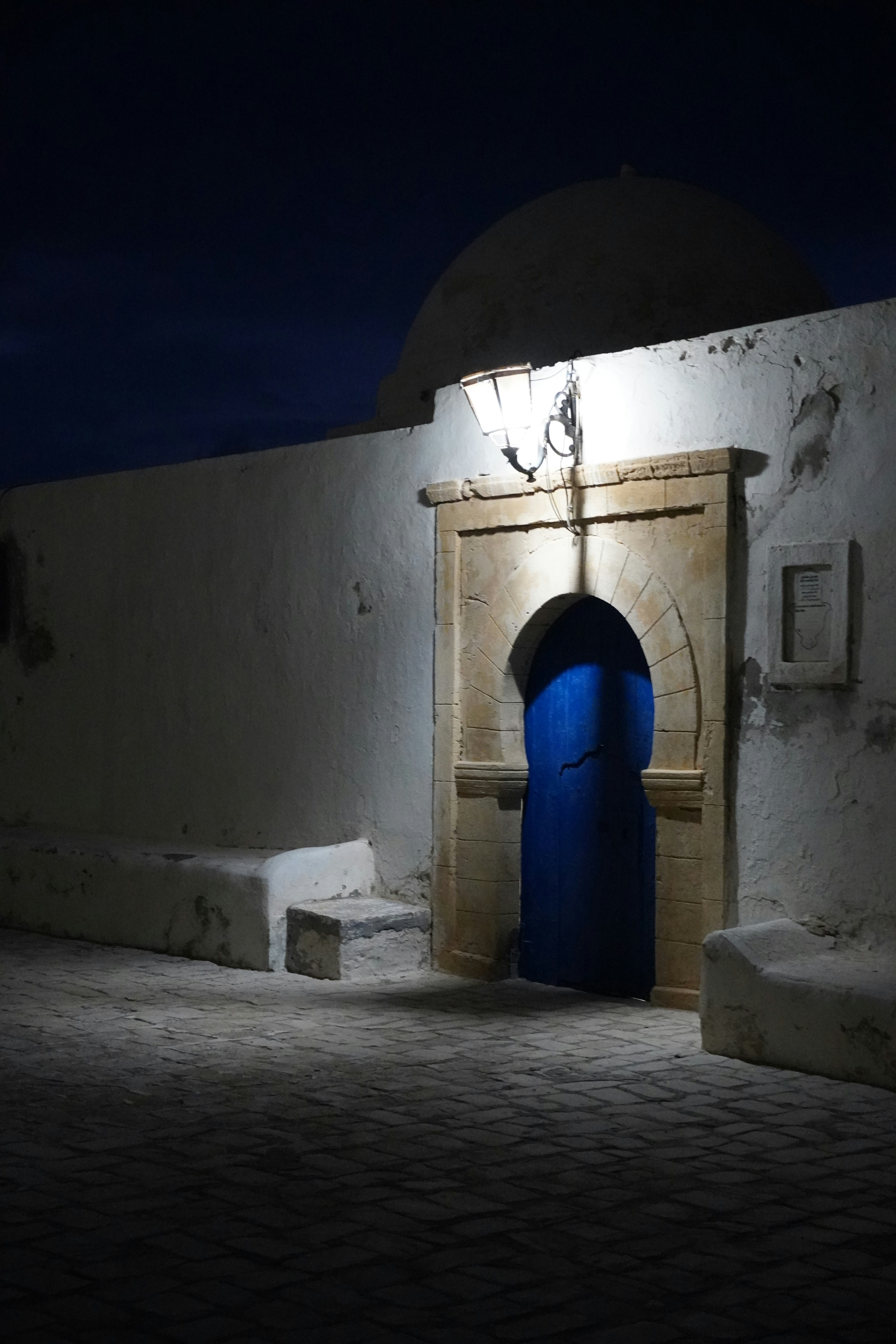 A bright blue door in a stone archway at night.