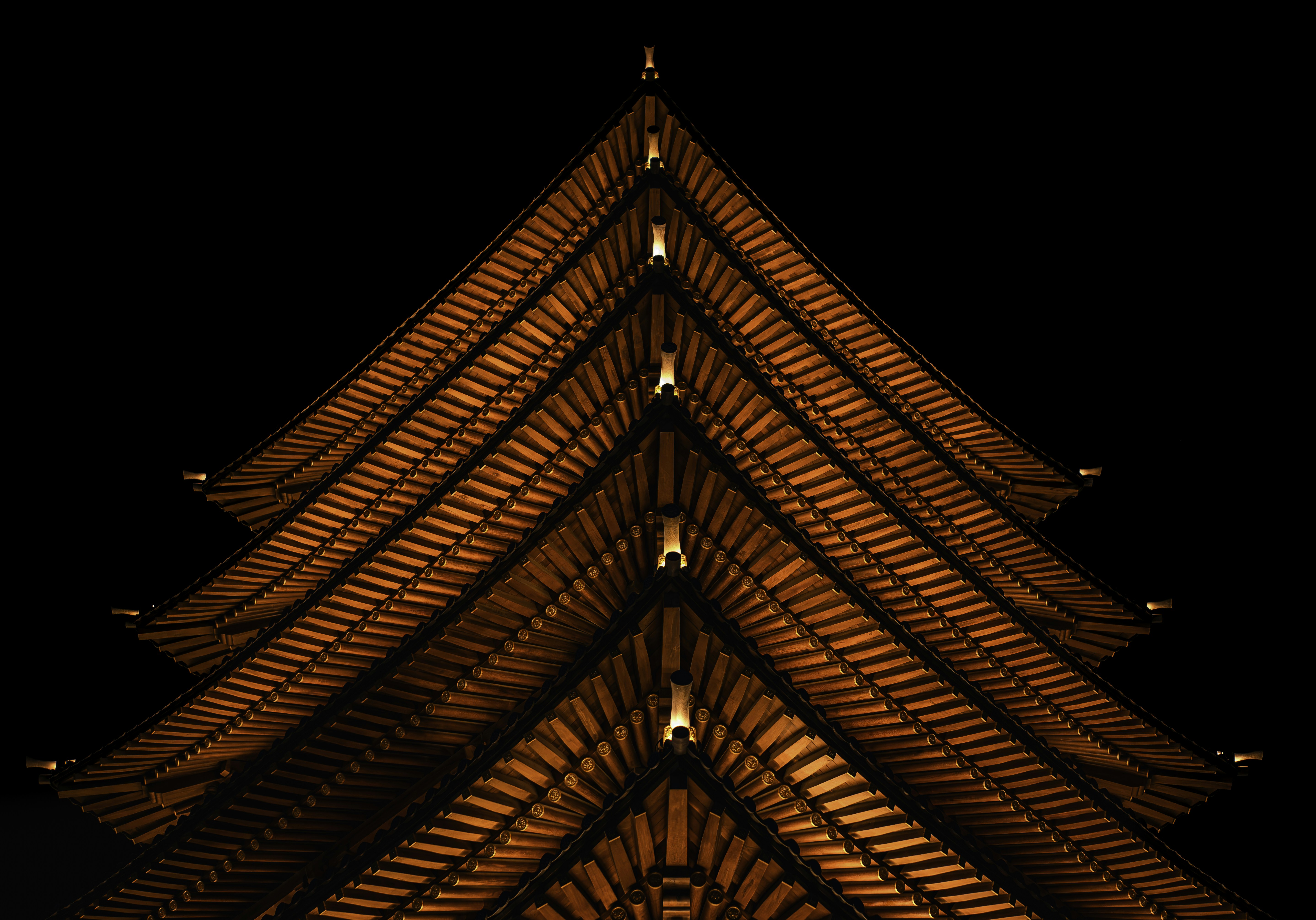 Illuminated japanese pagoda roof against dark sky