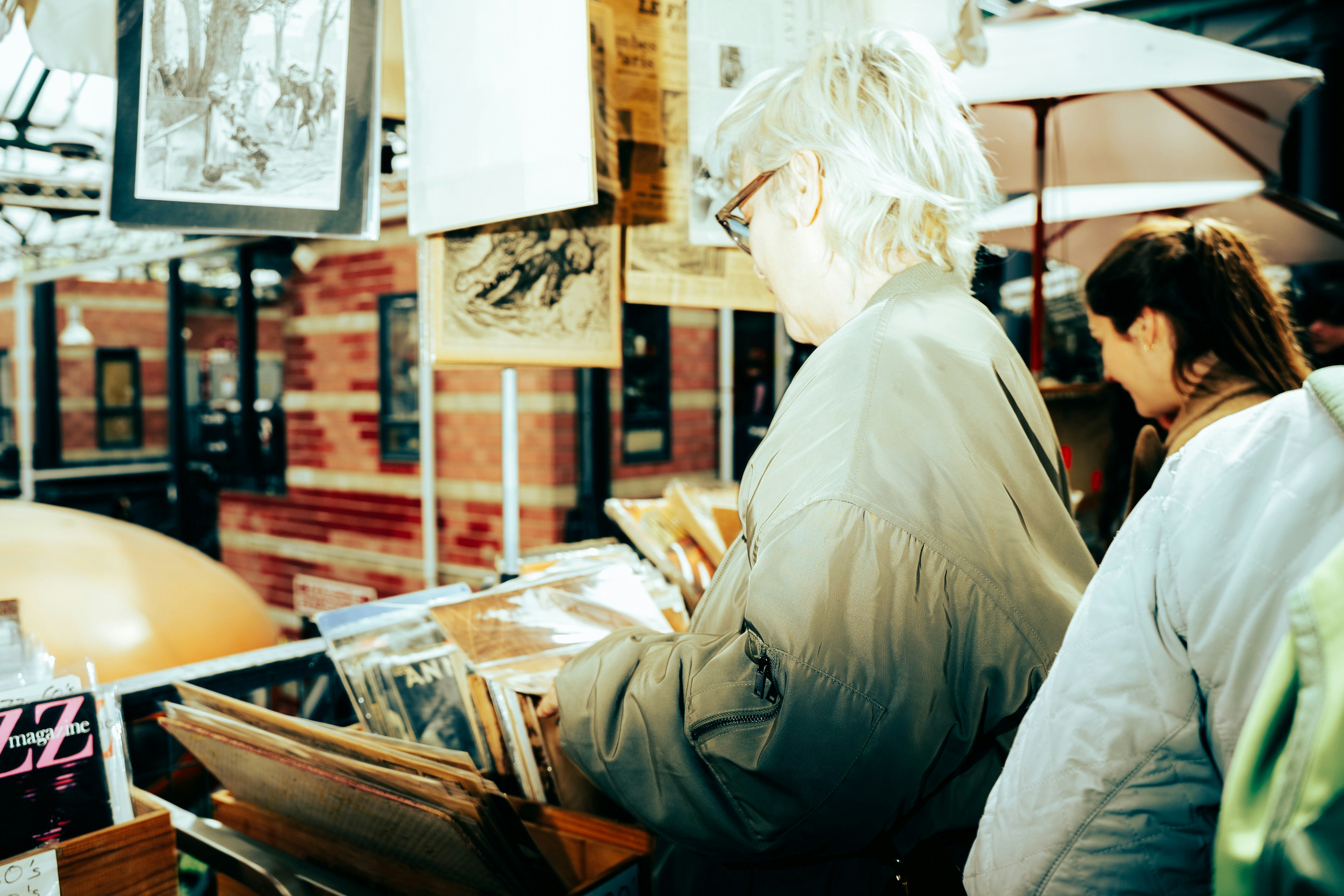 Elderly person browsing books at an outdoor market.