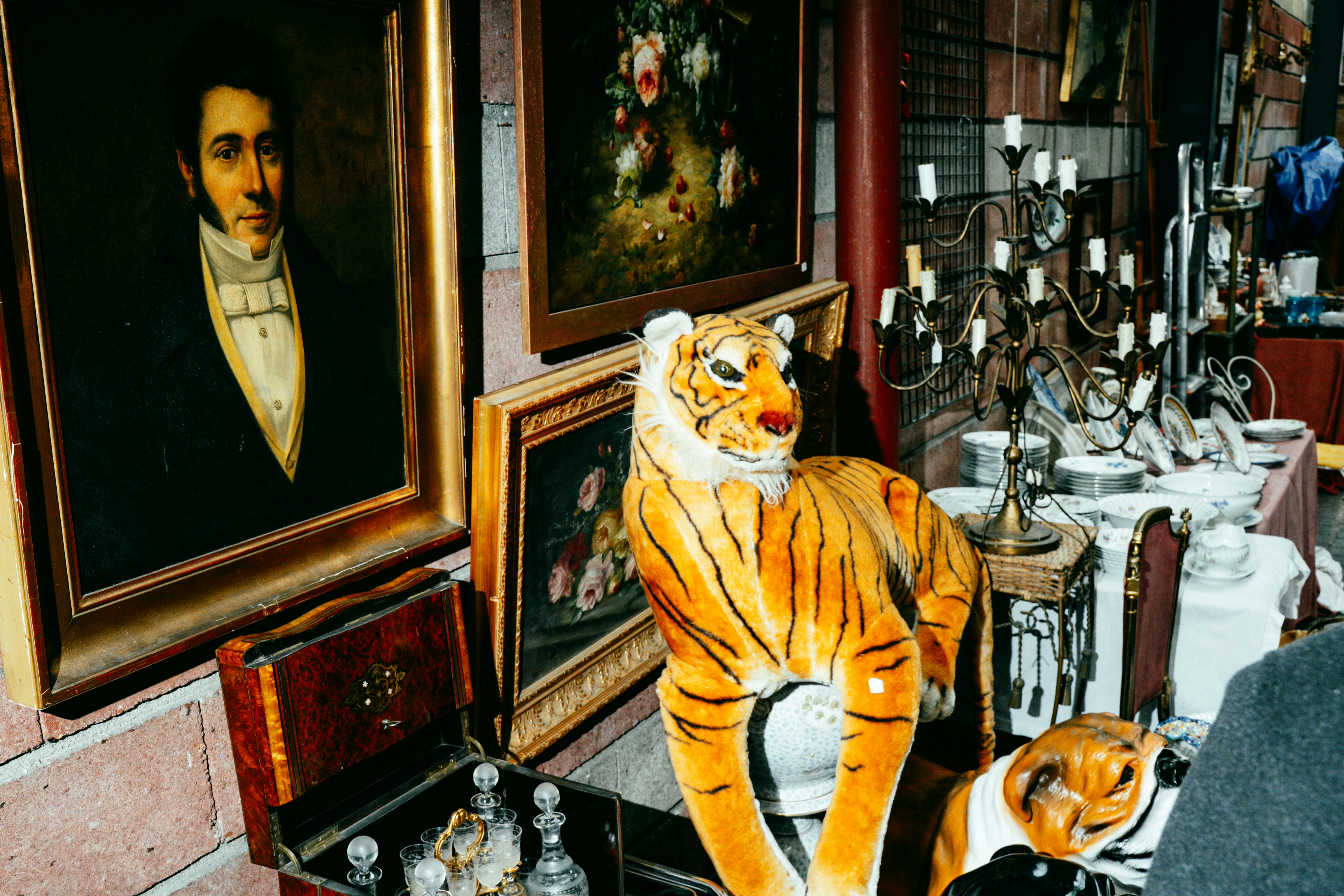 Statuette antiche di tigre esposte con dipinti e curiosità.