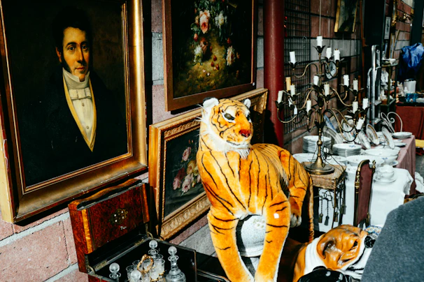 Antique tiger figurine displayed with paintings and curios