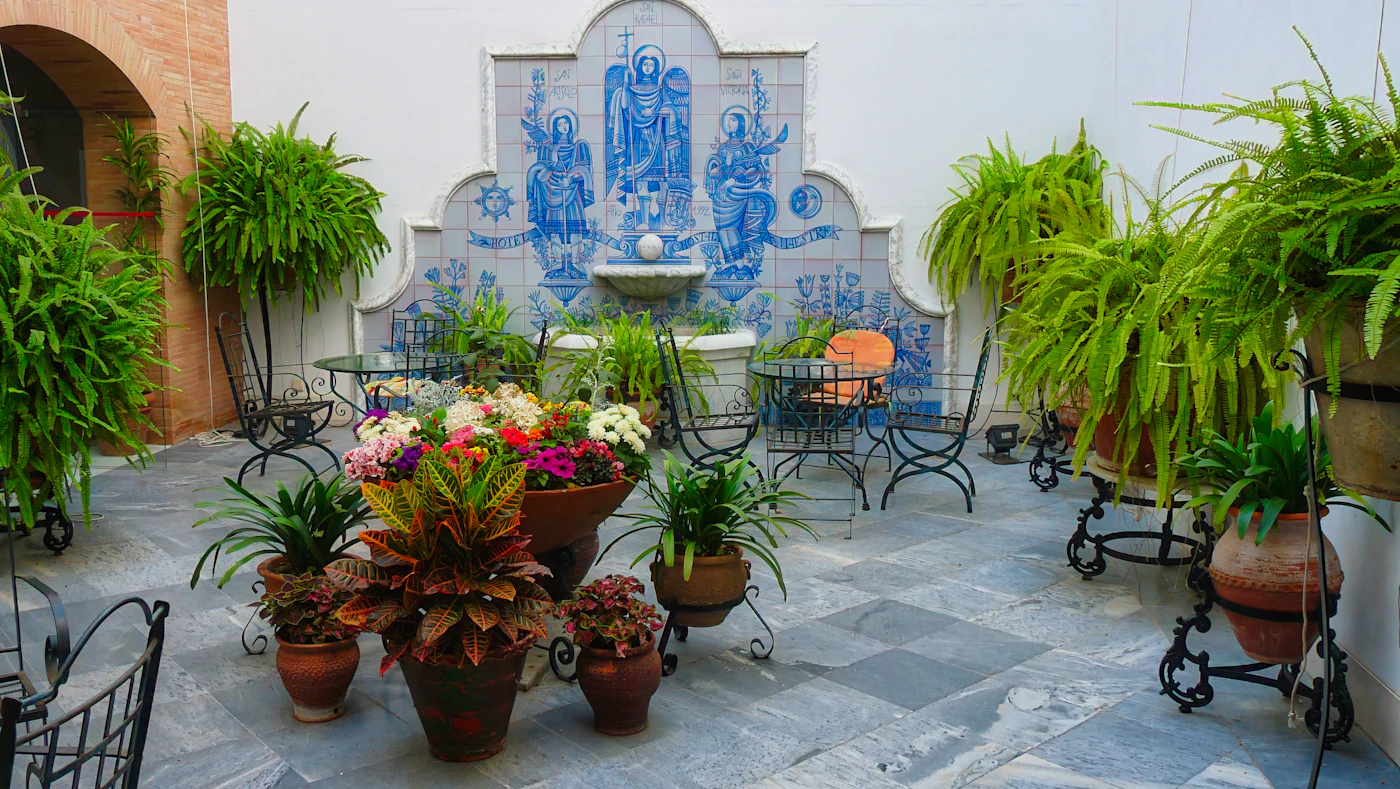 A tiled courtyard fountain surrounded by potted plants.