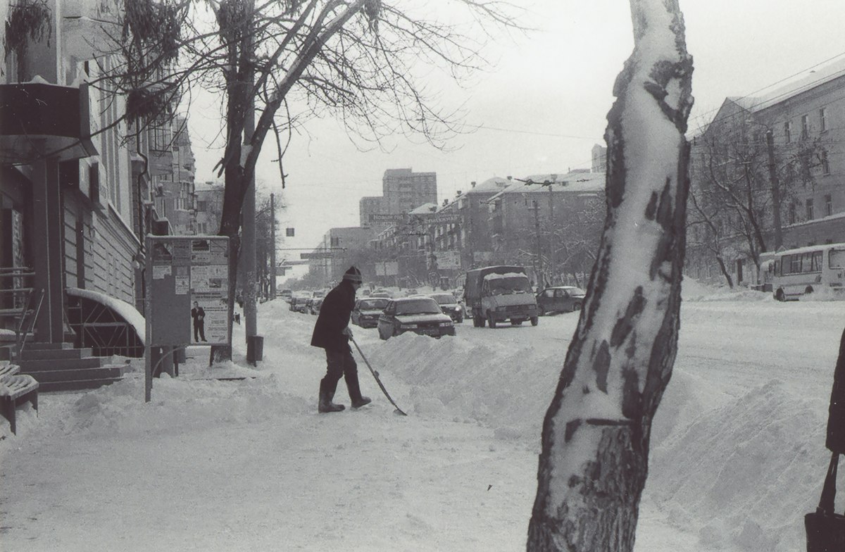 Person clearing snow on a street - snow pusher for seniors