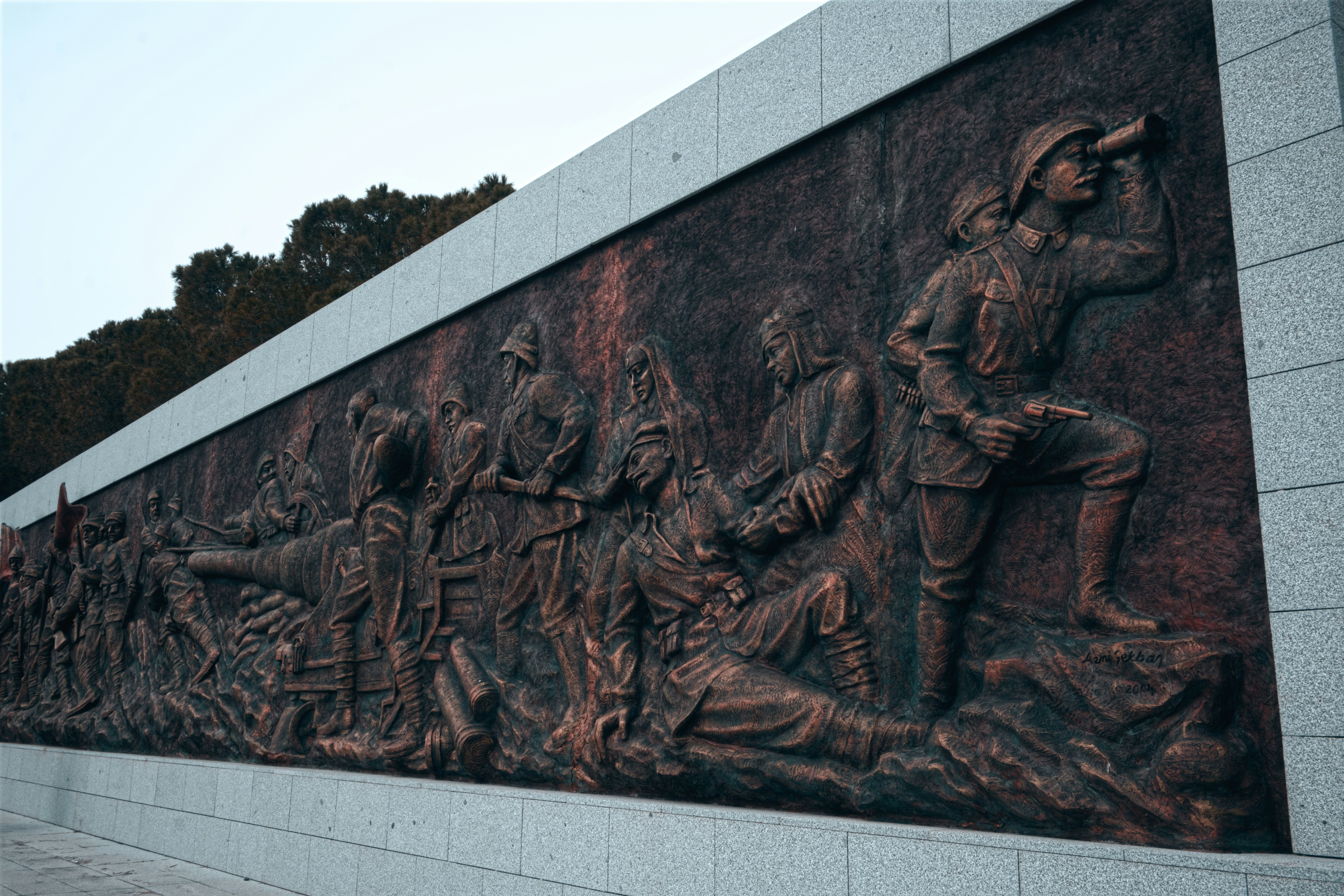 Escultura em relevo de bronze representando soldados em batalha