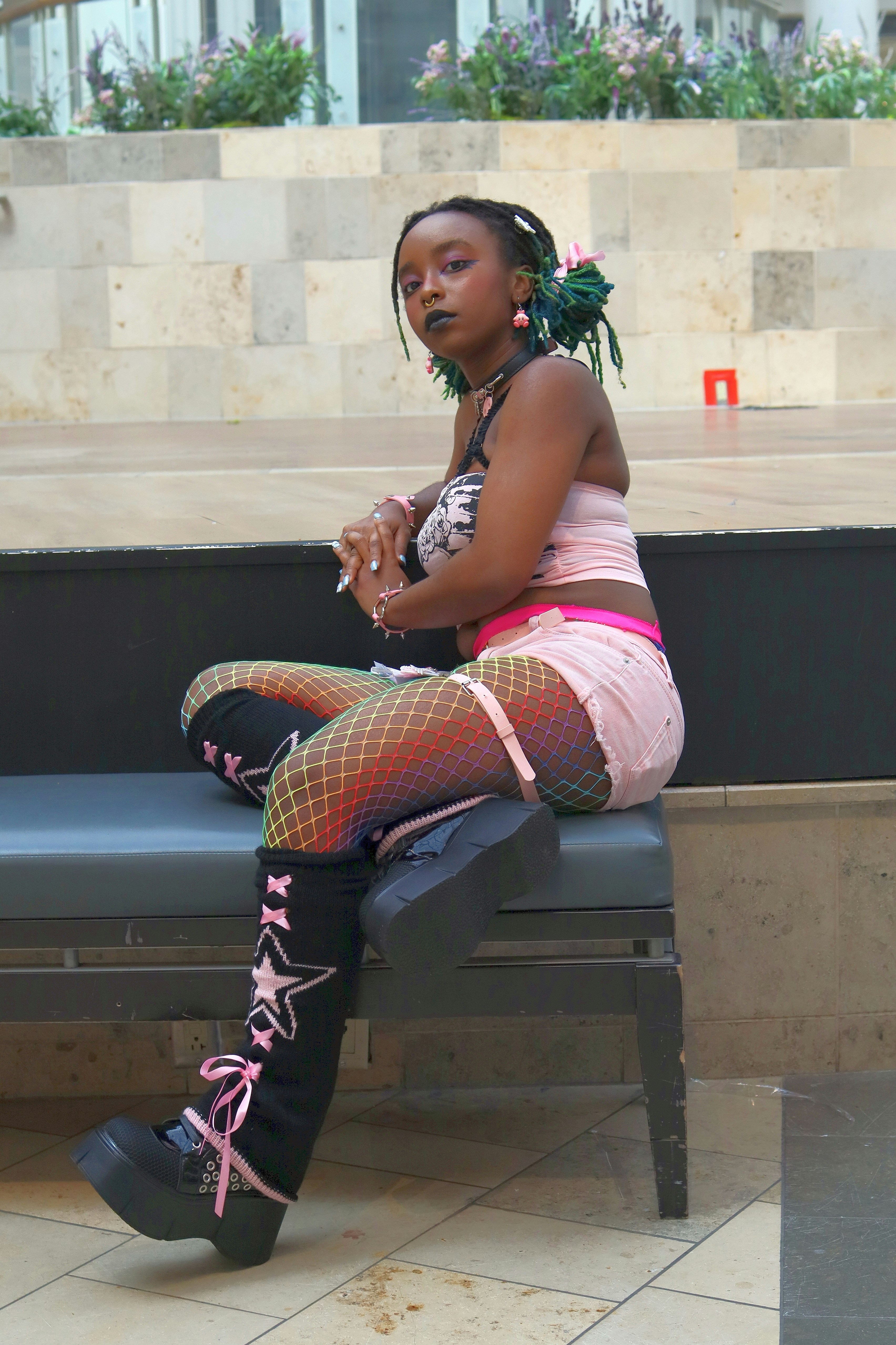A young woman with green hair sits on a bench.