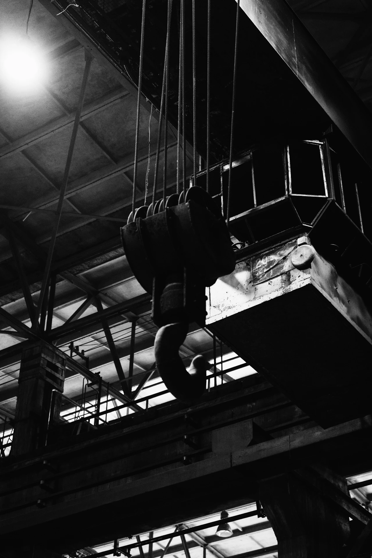Kait crane industri menggantung dari struktur atap di dalam bangunan pabrik