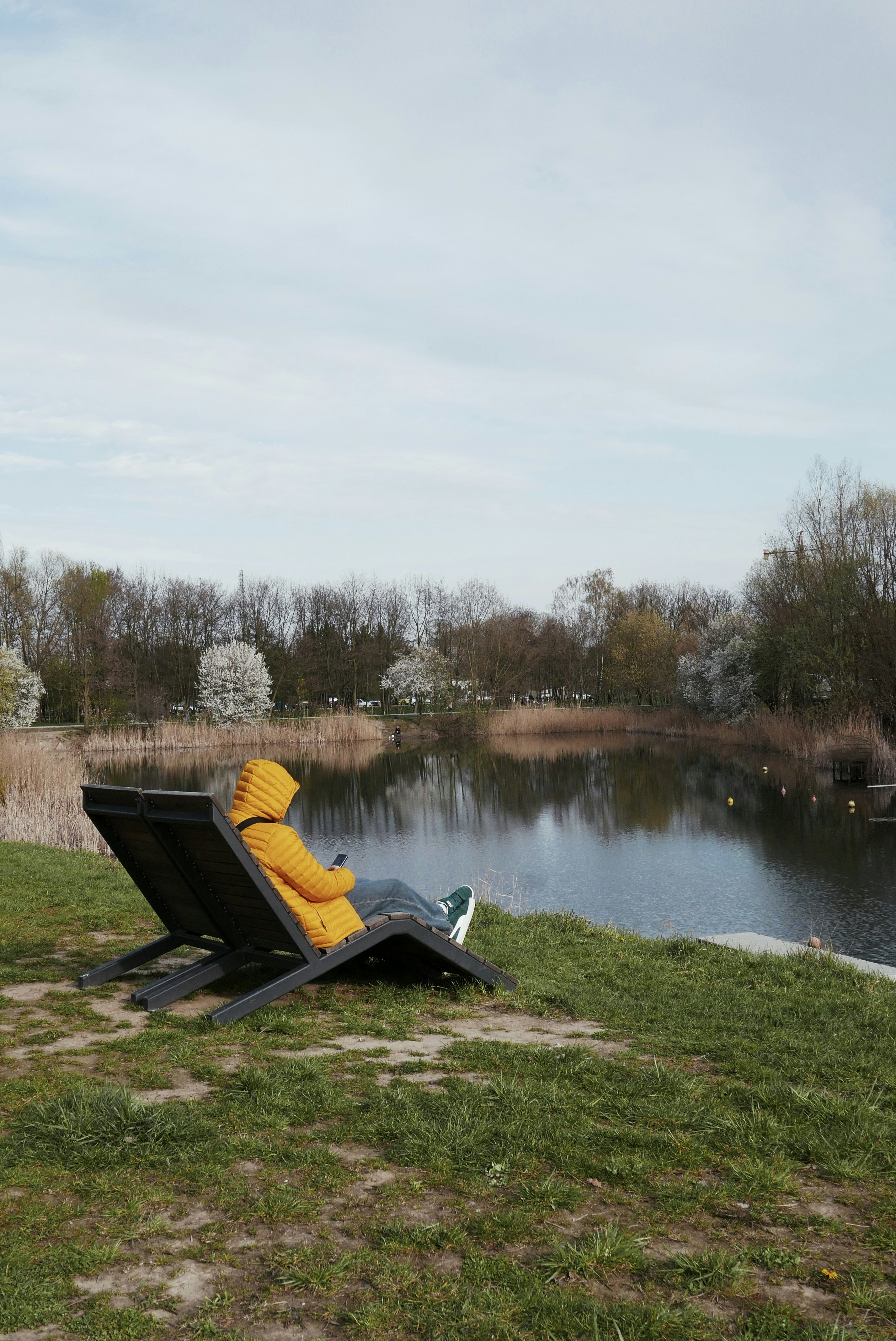 Person in der gelben Jacke entspannt sich am See
