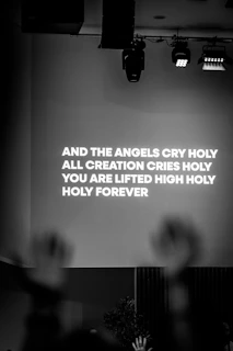 Stage screen displays lyrics with hands raised
