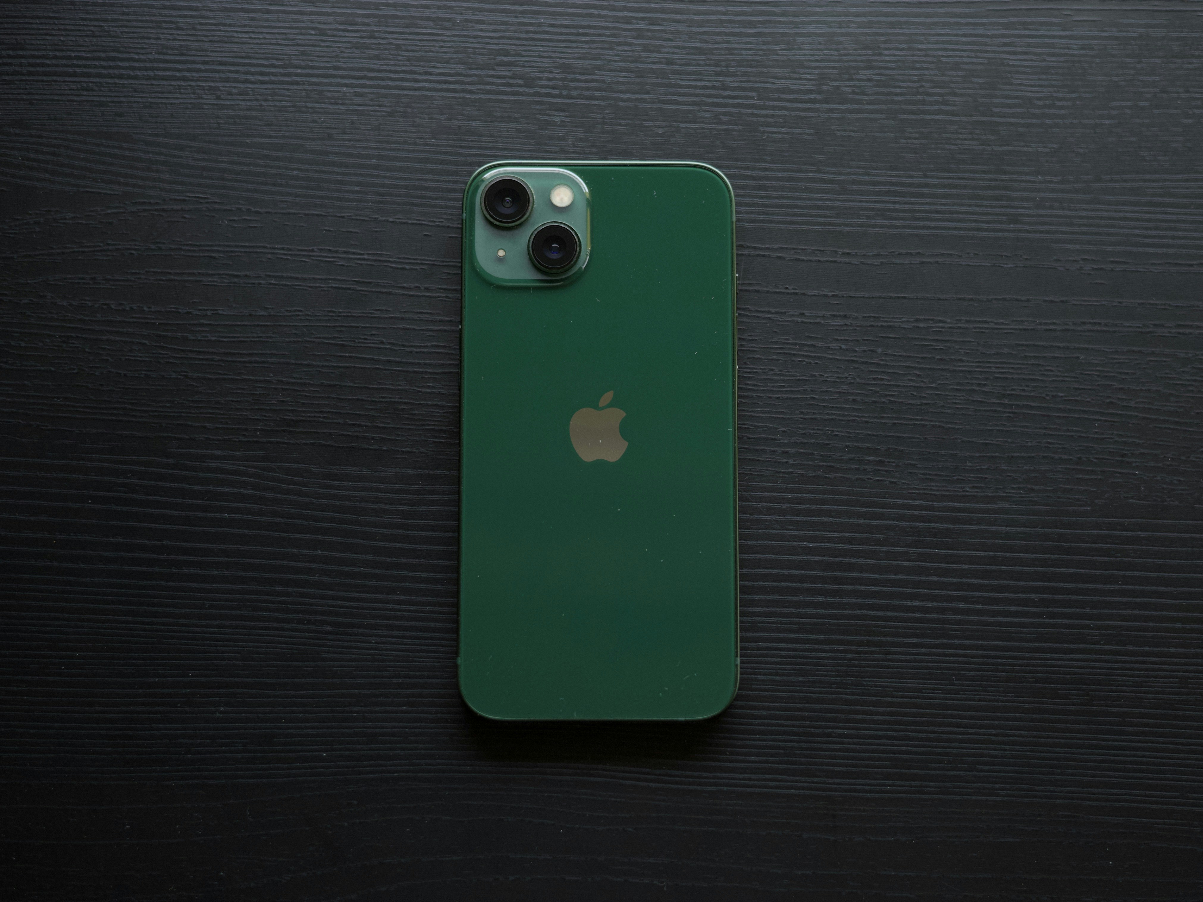 iPhone verde sobre una superficie de textura oscura
