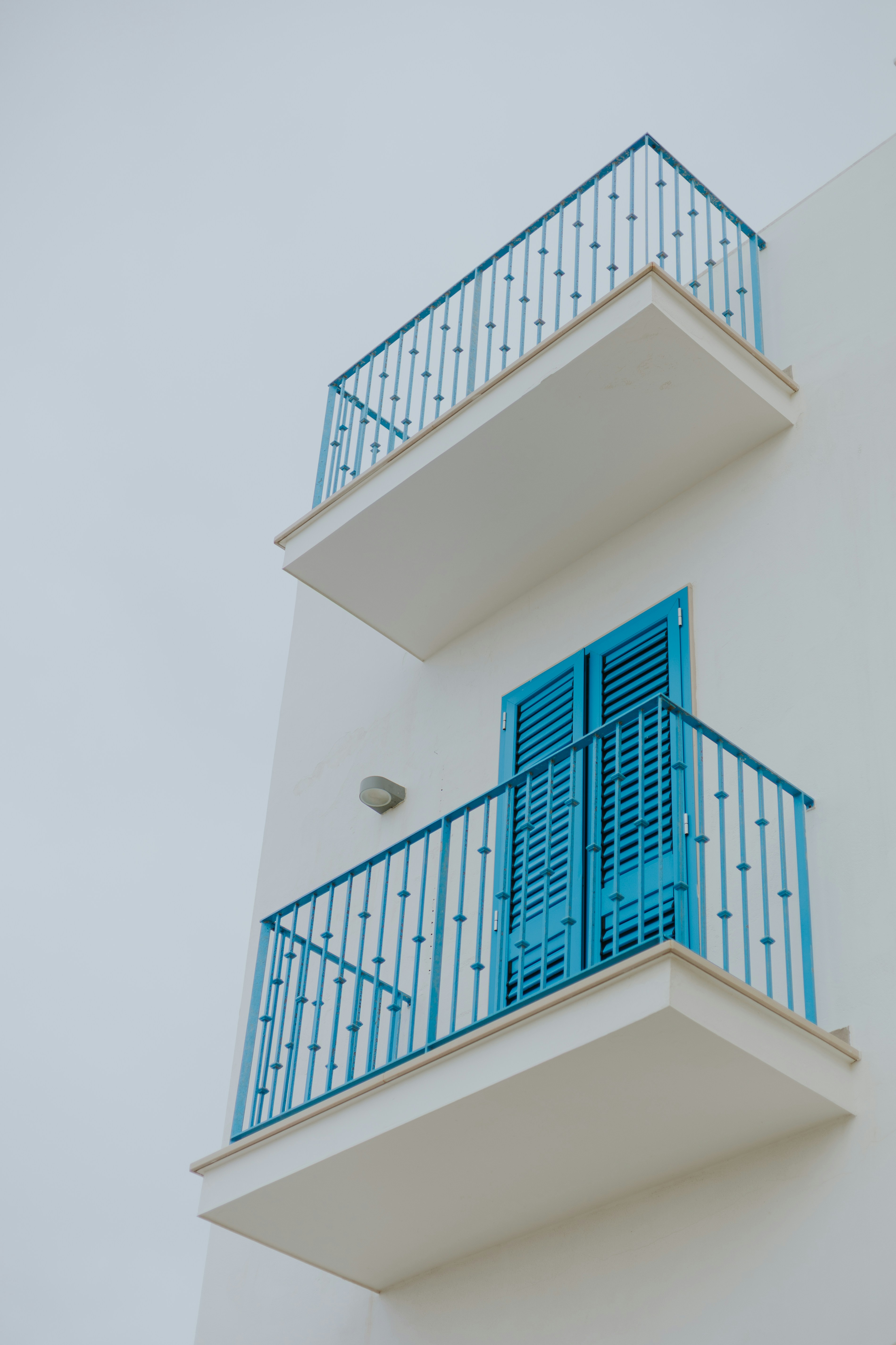 Weißes Gebäude mit blauen Balkonen und Fensterläden