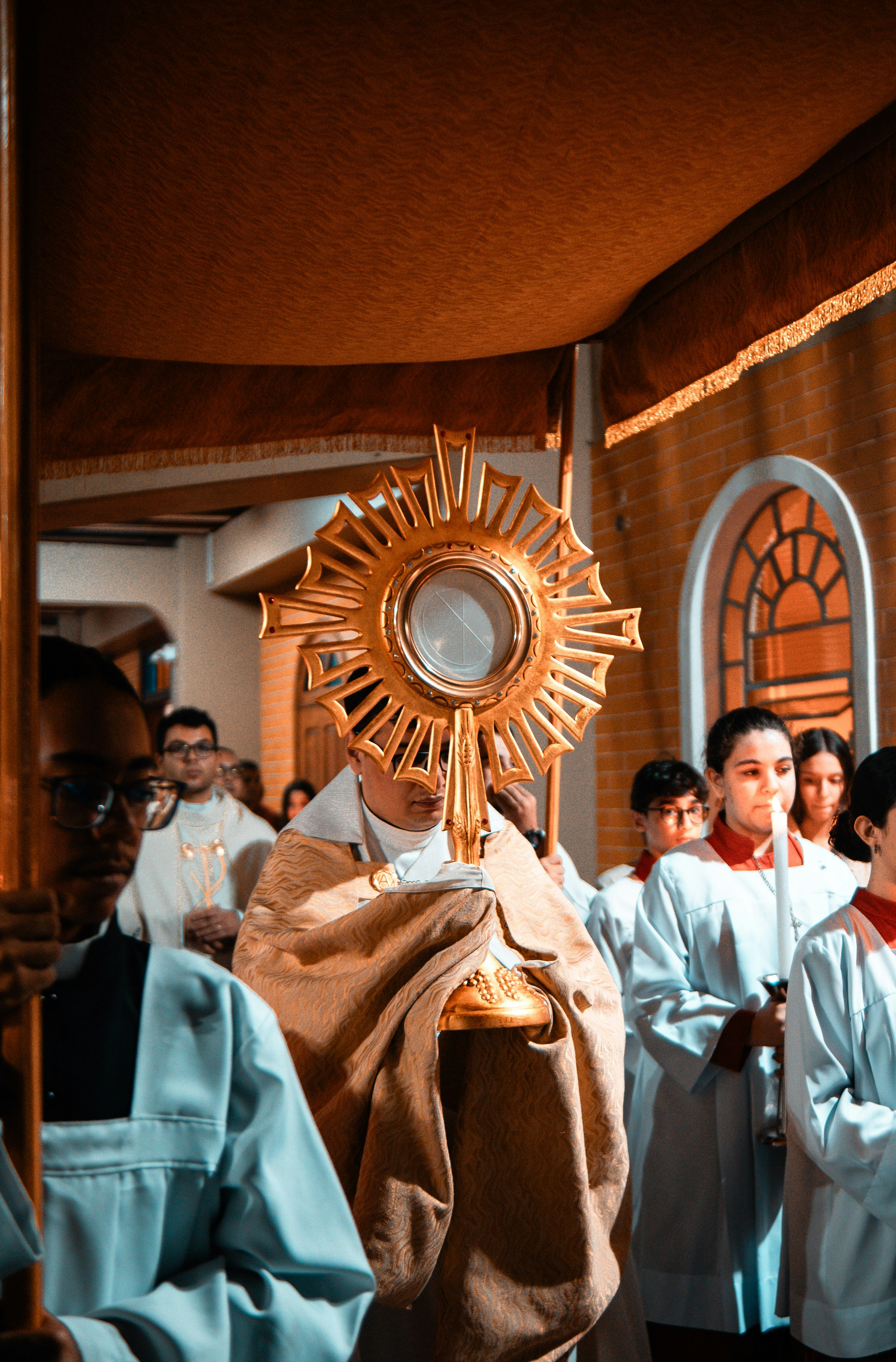 Membro do clero segurando uma custódia durante uma procissão religiosa.