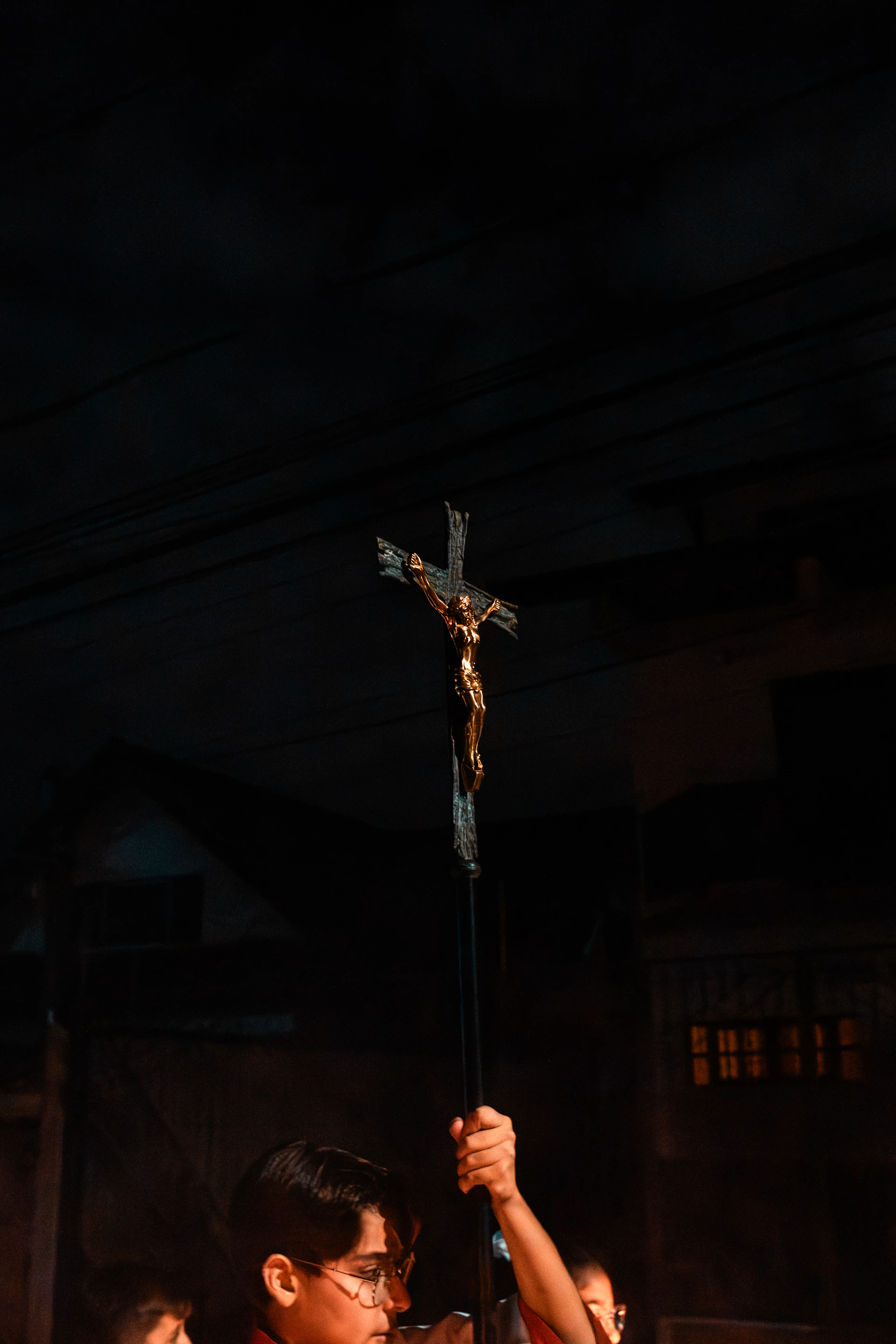 A person holds a crucifix high during a religious ceremony.