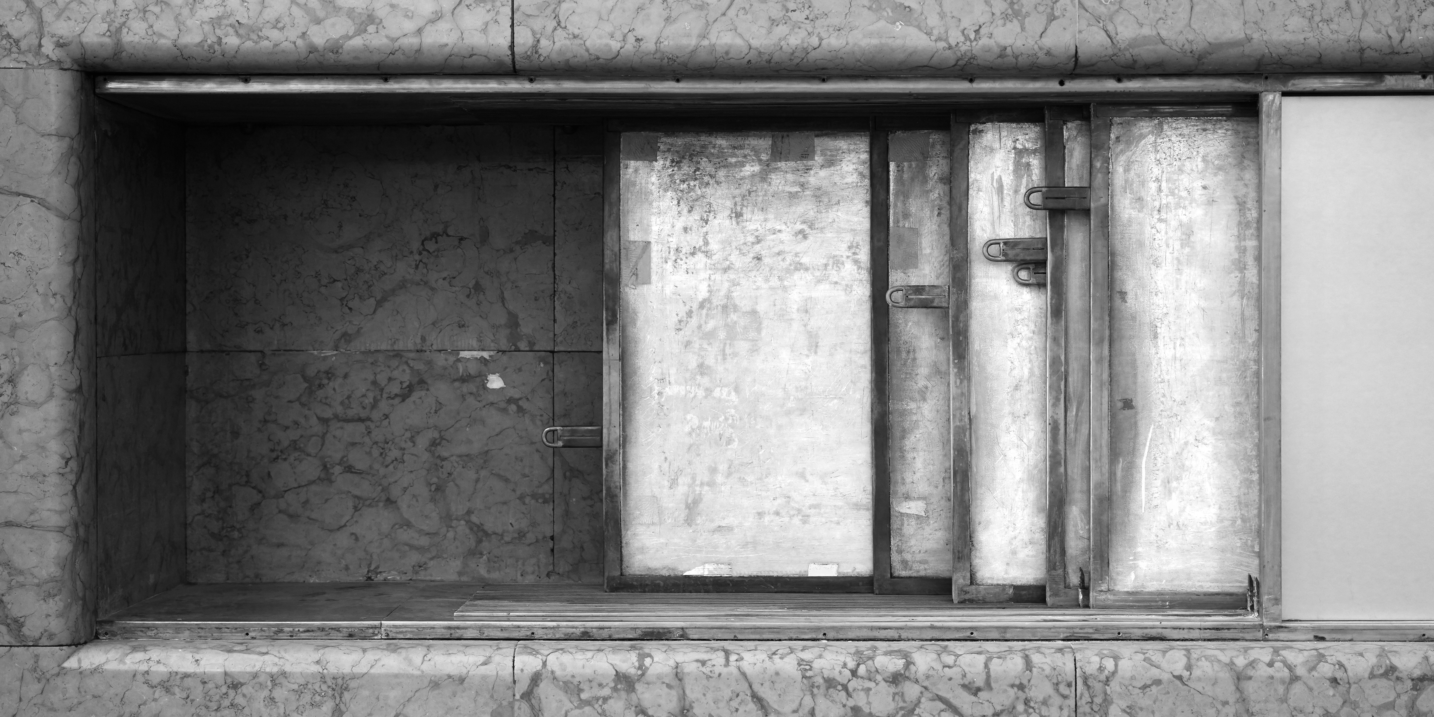 A close-up of a marble-lined niche with metal doors.
