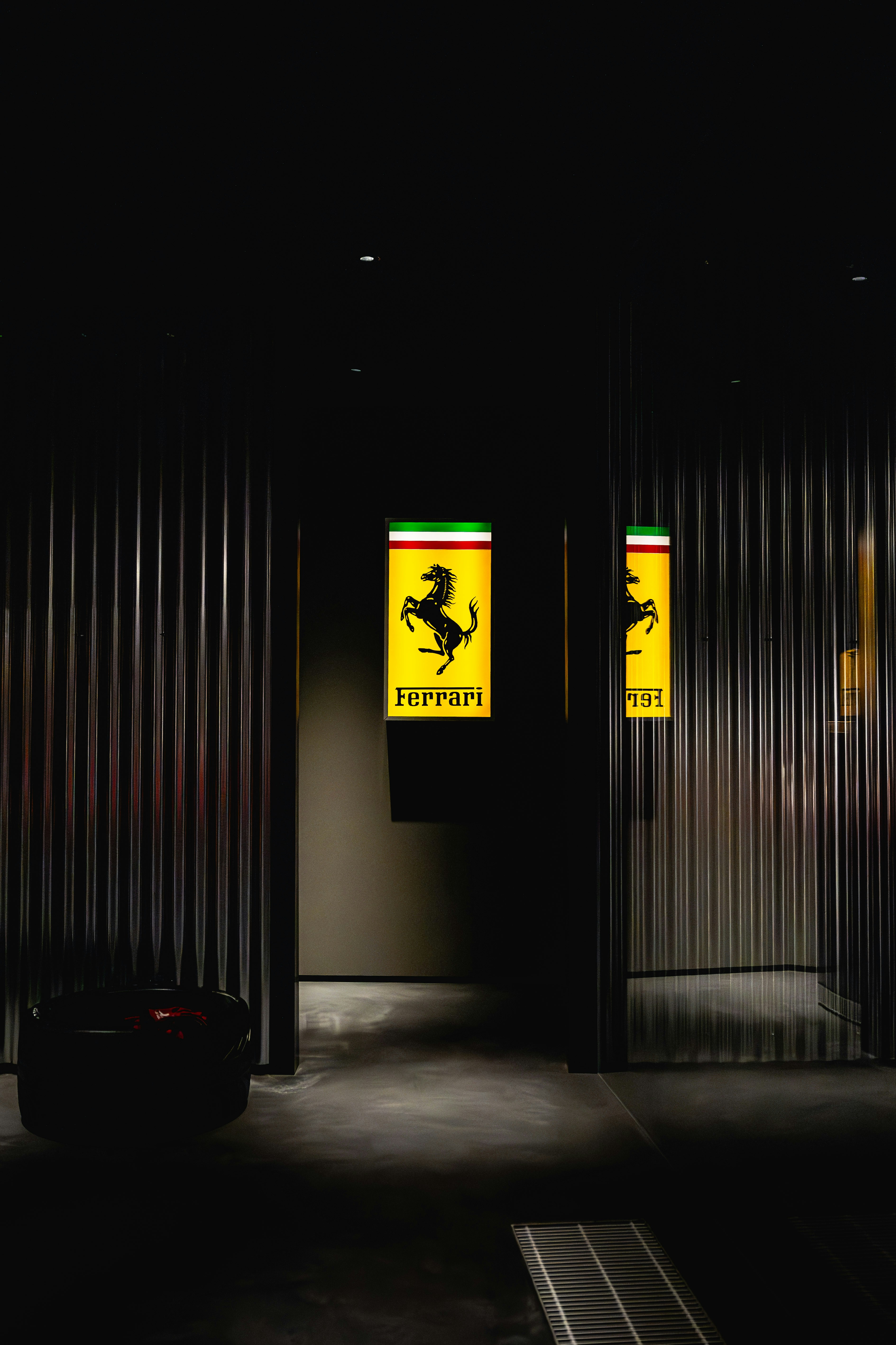Ferrari logos hang in a dark, modern showroom.