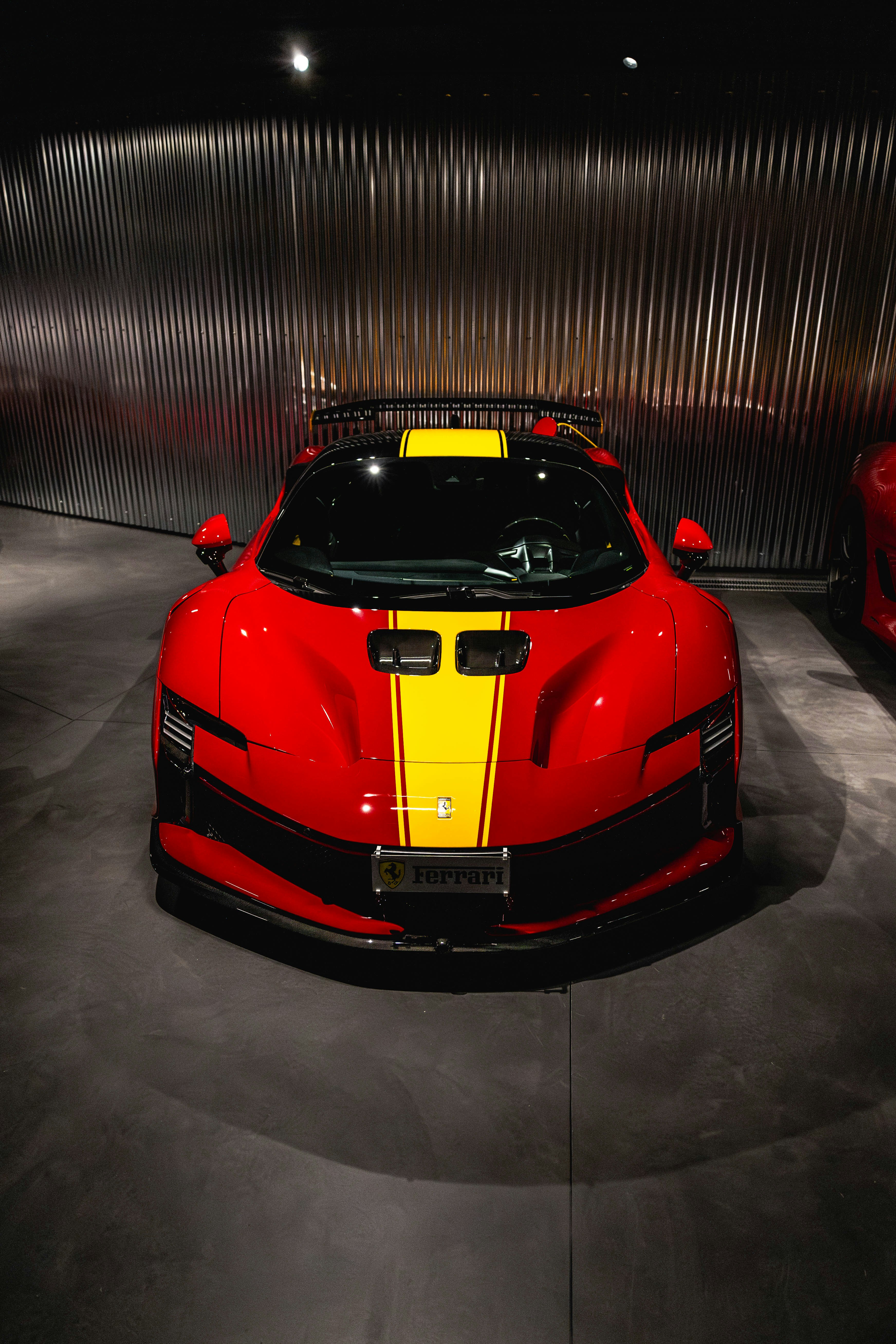 Red sports car with yellow stripes in a showroom.