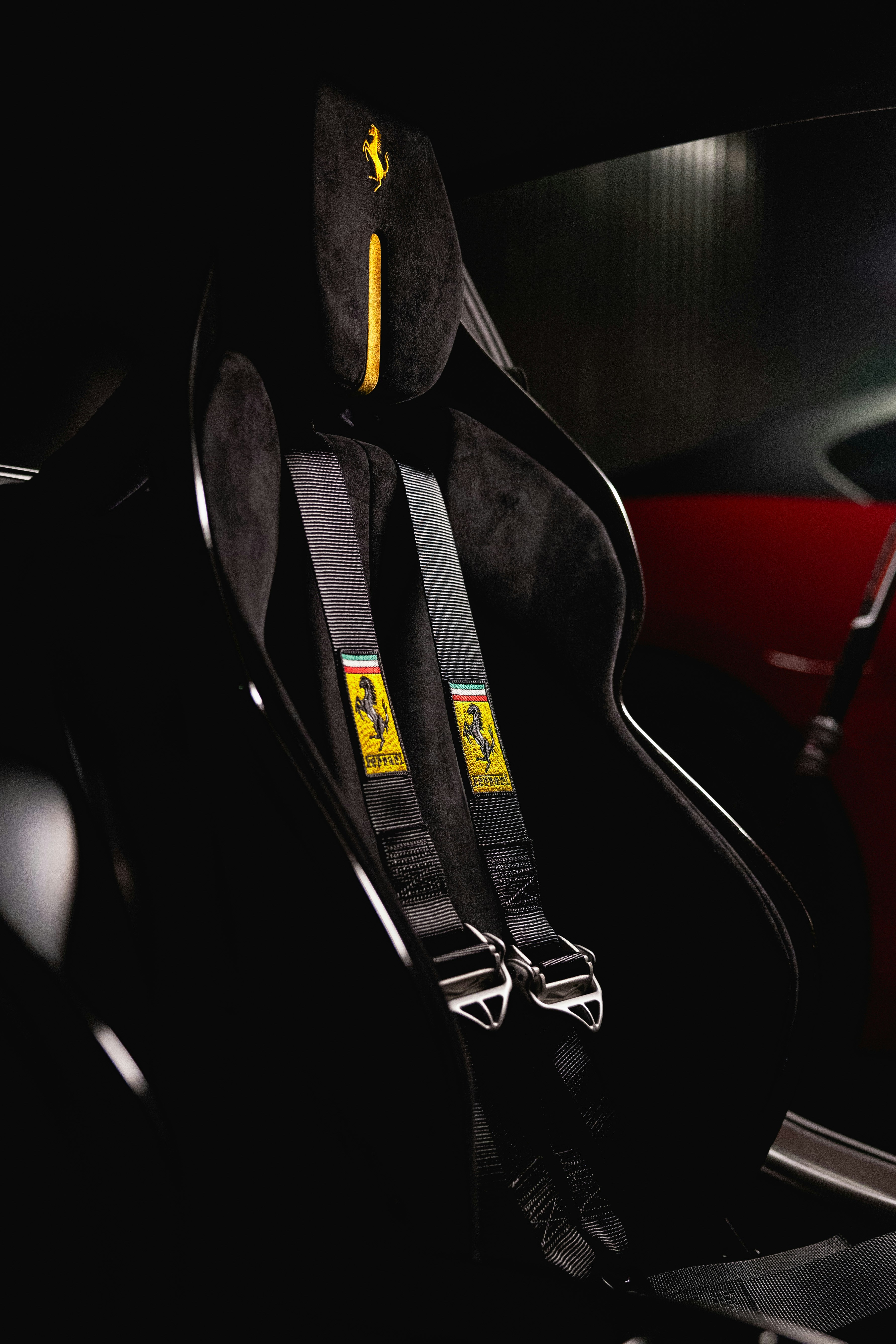 Black racing seat with yellow ferrari logo and harness.