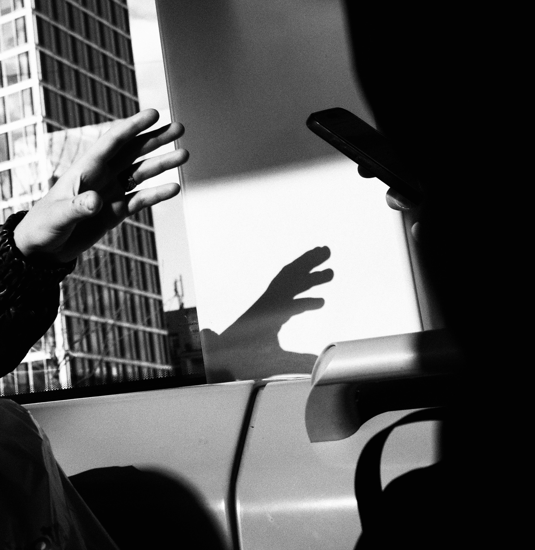 Hands reaching out, one holding a smartphone.