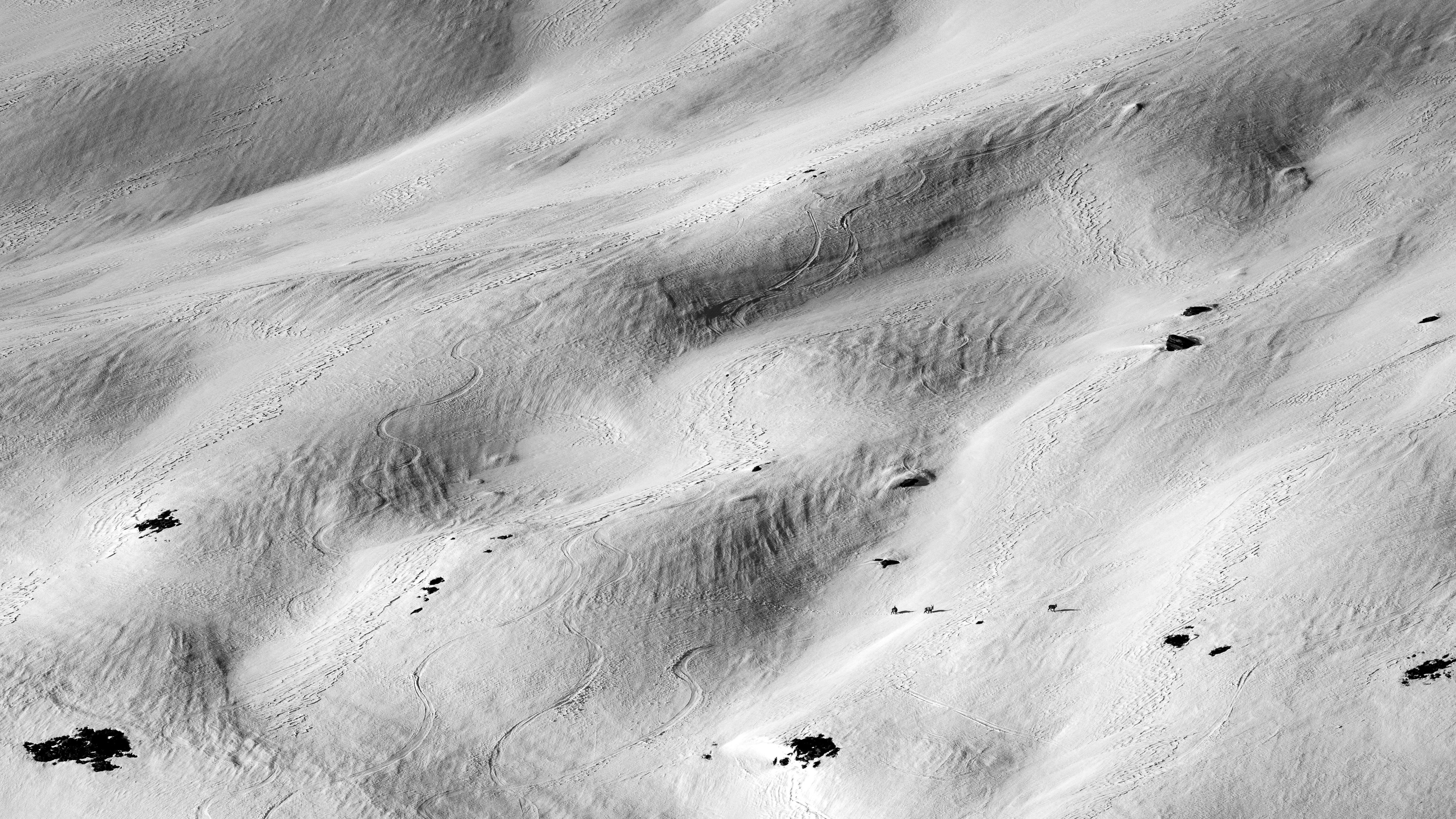 Textured sand dunes with small dark rocks scattered rocks.