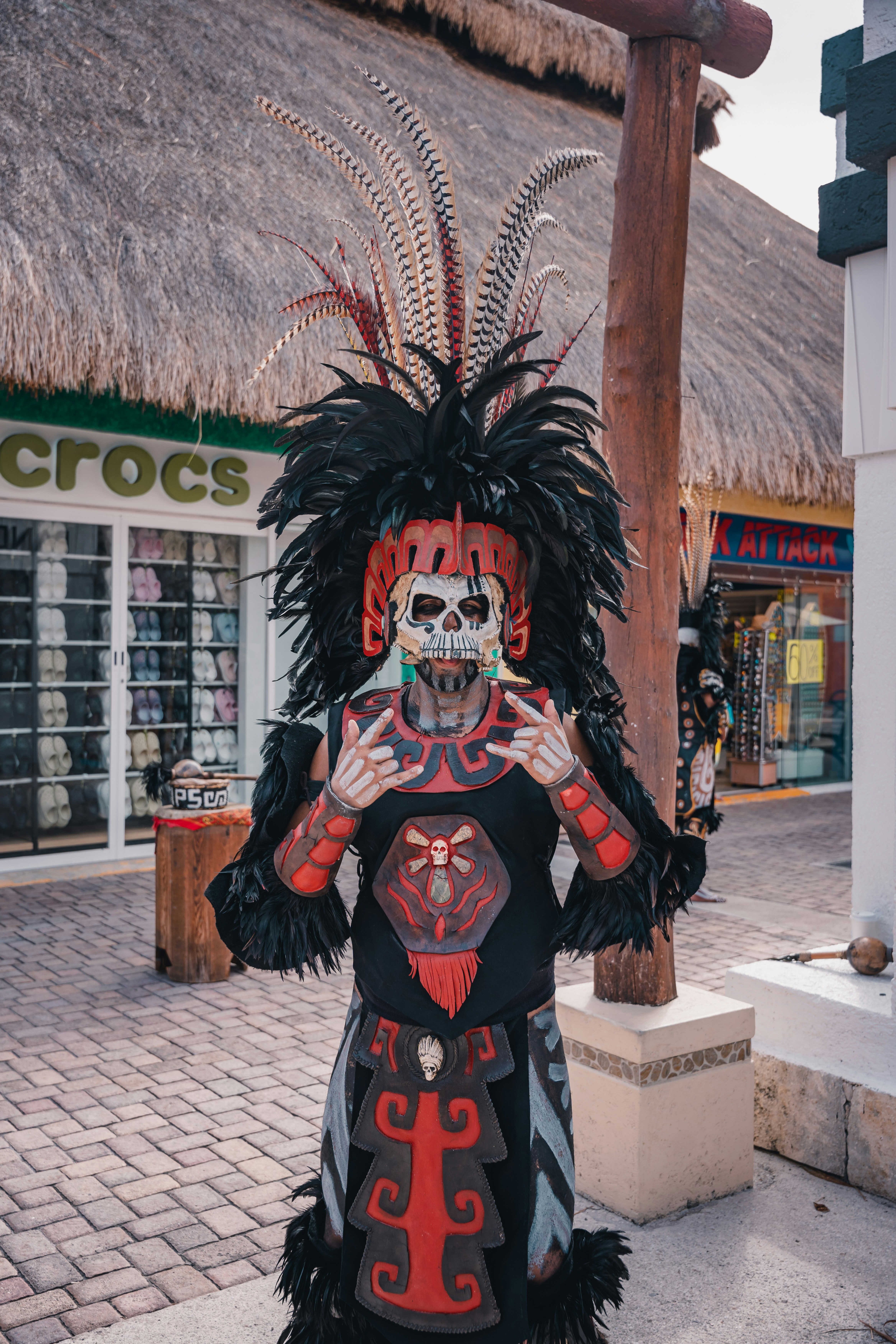 Person in elaborate skull mask and feathered headdress