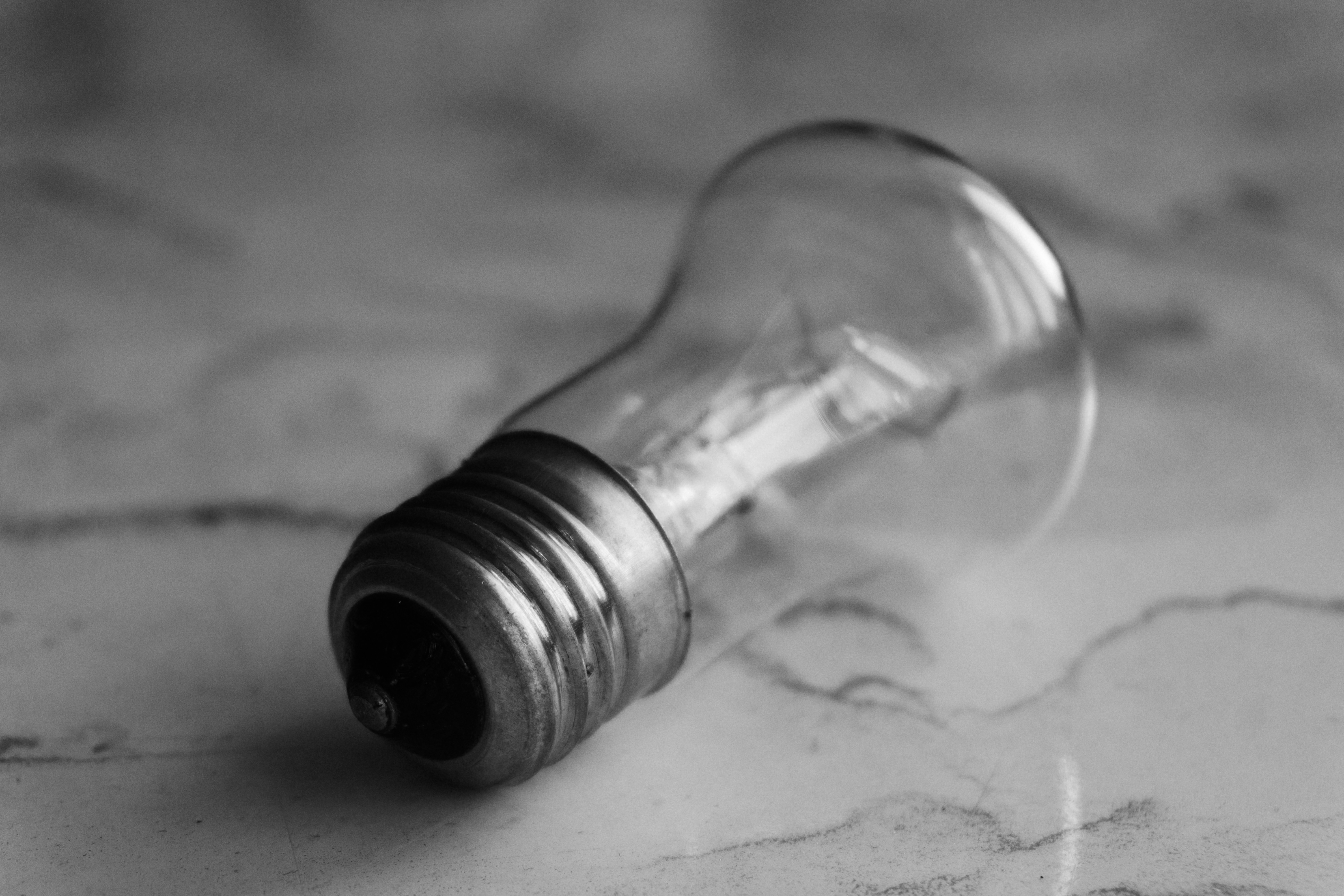 A clear glass lightbulb rests on a marbled surface.