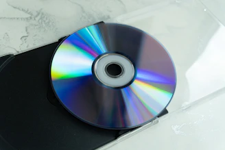 A shiny cd reflecting rainbow colors on a surface.