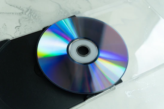 A shiny cd reflecting rainbow colors on a surface.