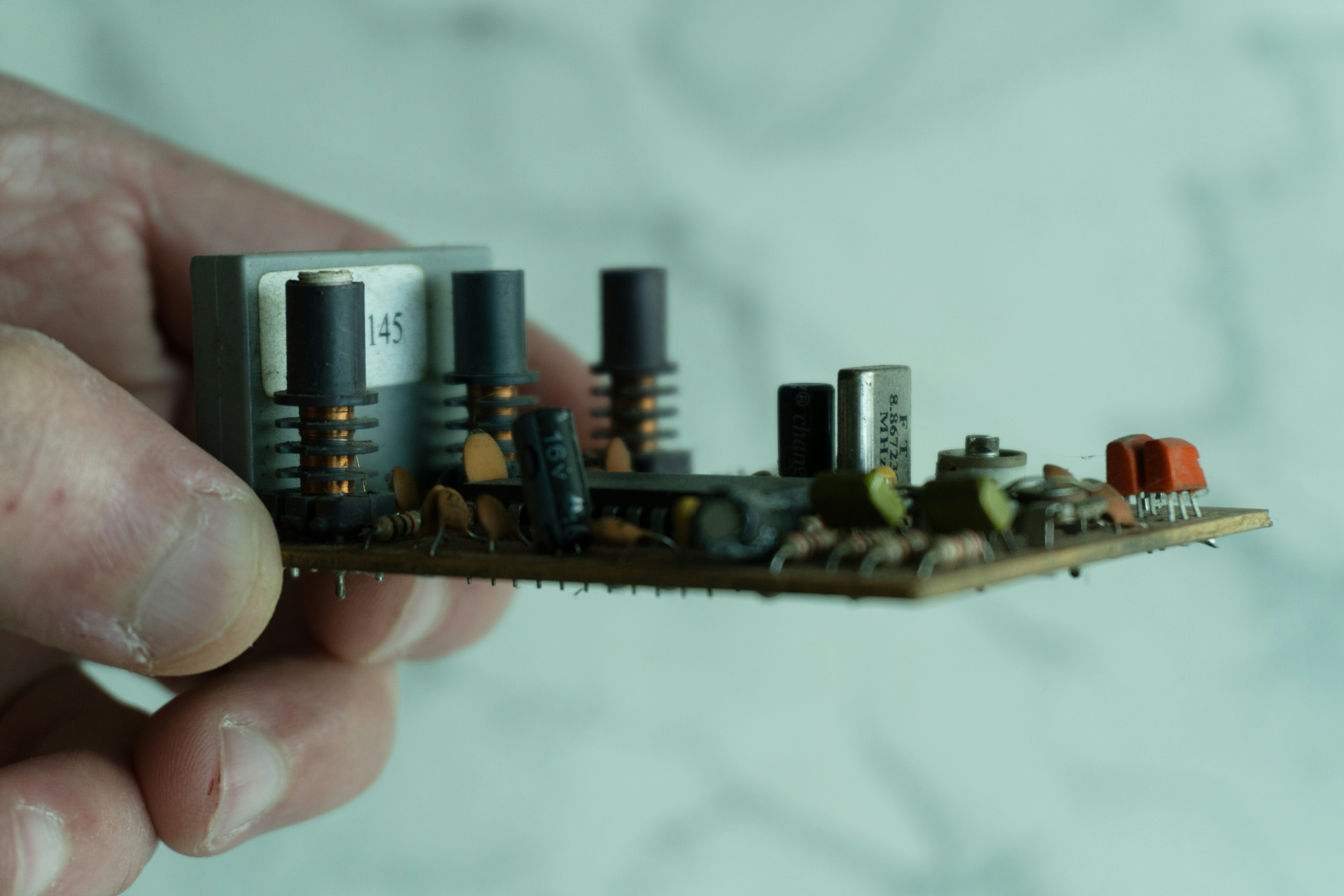 Hand holding a complex electronic circuit board with components.