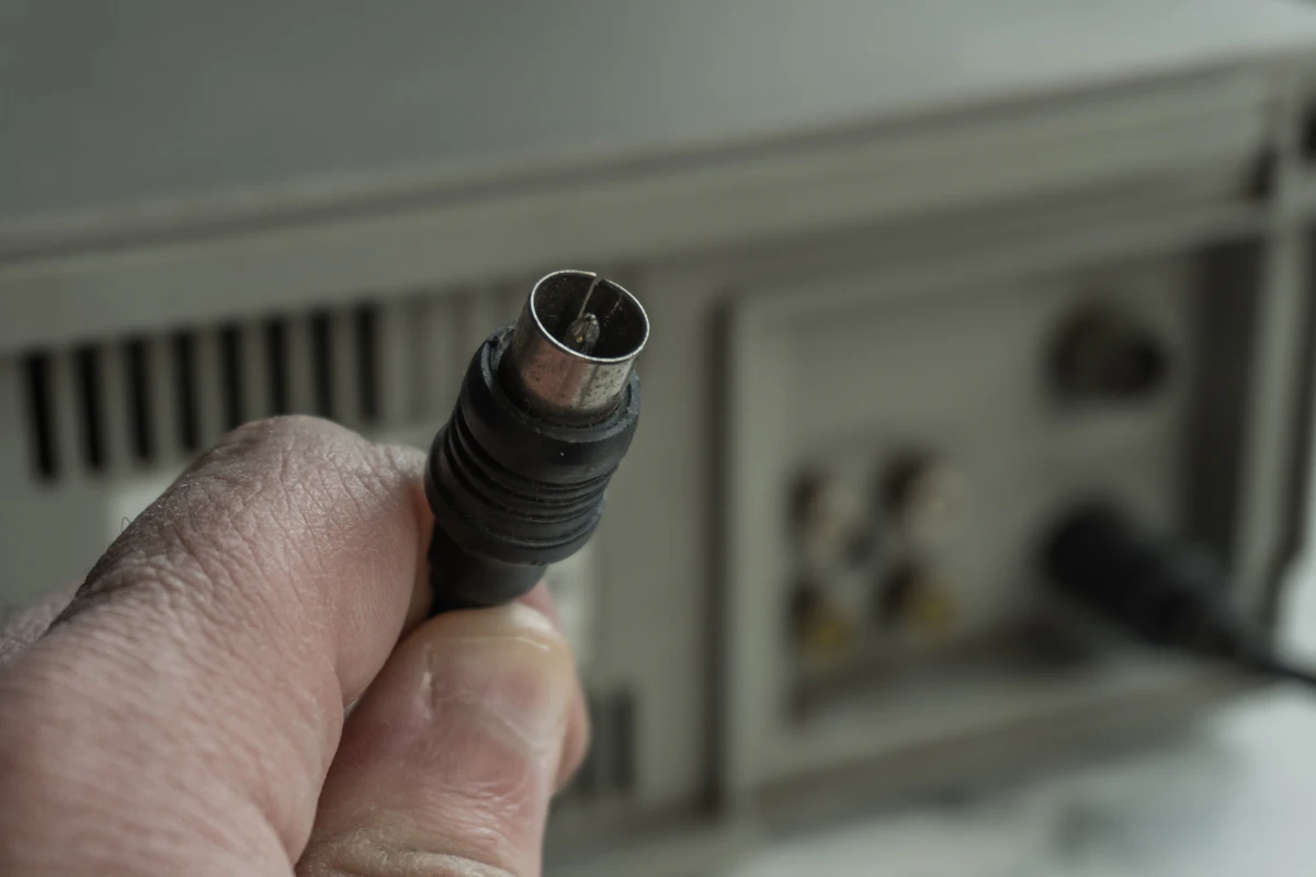 Hand holding a coaxial cable connector next to radio equipment