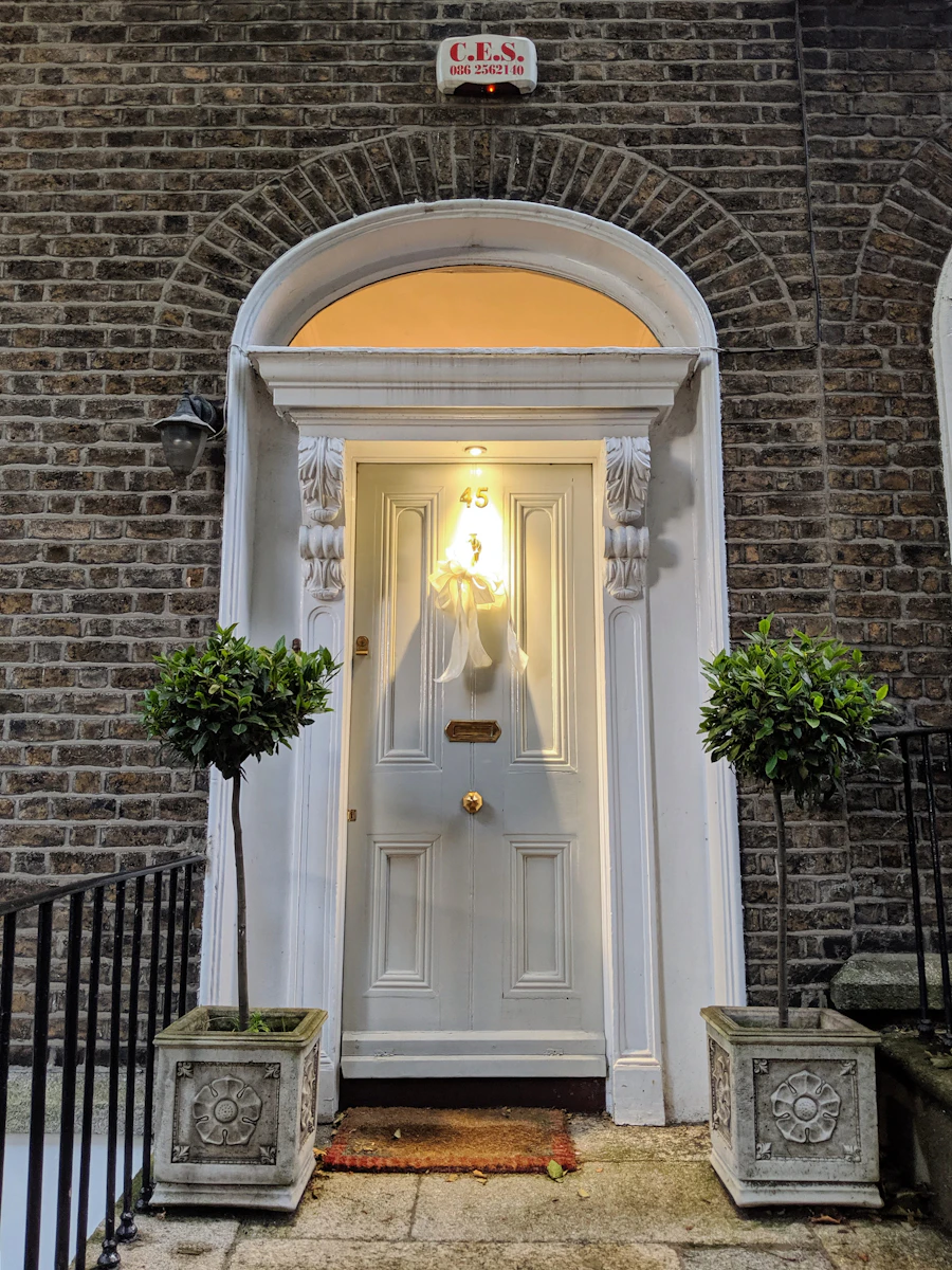 Classic stone residence entrance with gas lanterns and manicured topiary
